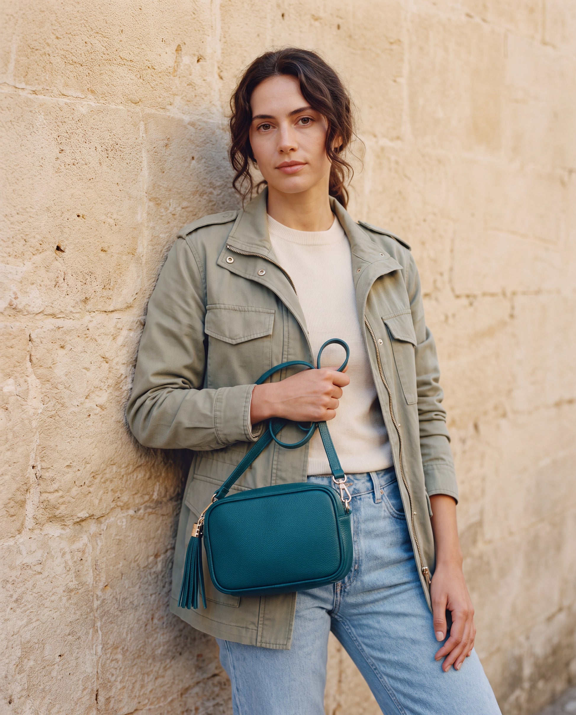 Model with the Teal Éloise Leather Tassel Camera Bag by Clemés against a warm stone wall