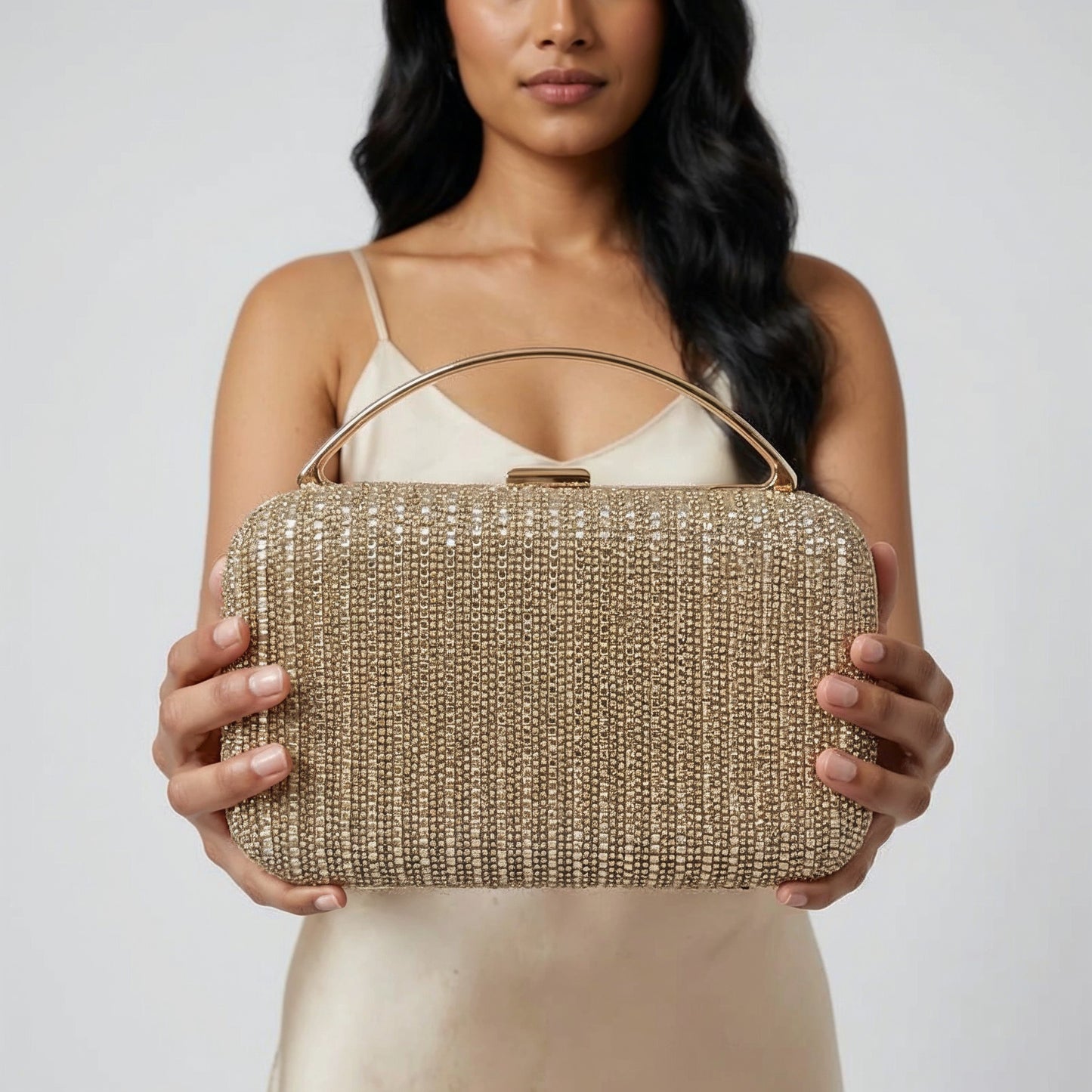 Model presenting the Gold Odette Crystal Minaudière Clutch to the camera, studio hero shot