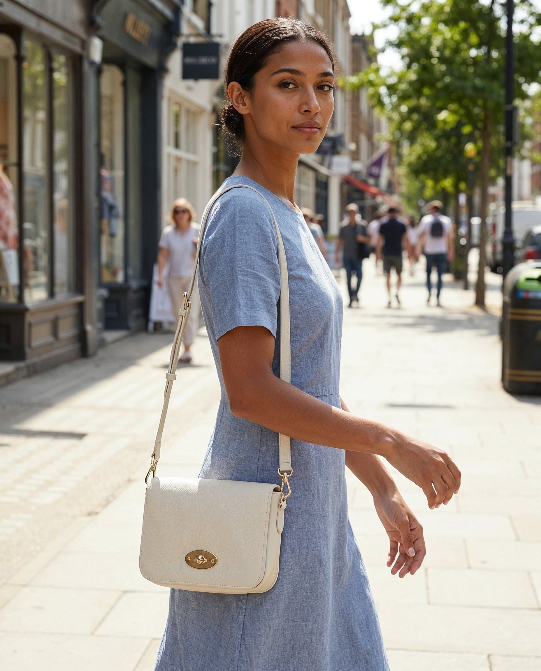 Woman carrying the Oyster Chiara crossbody bag on a sunlit shopping street