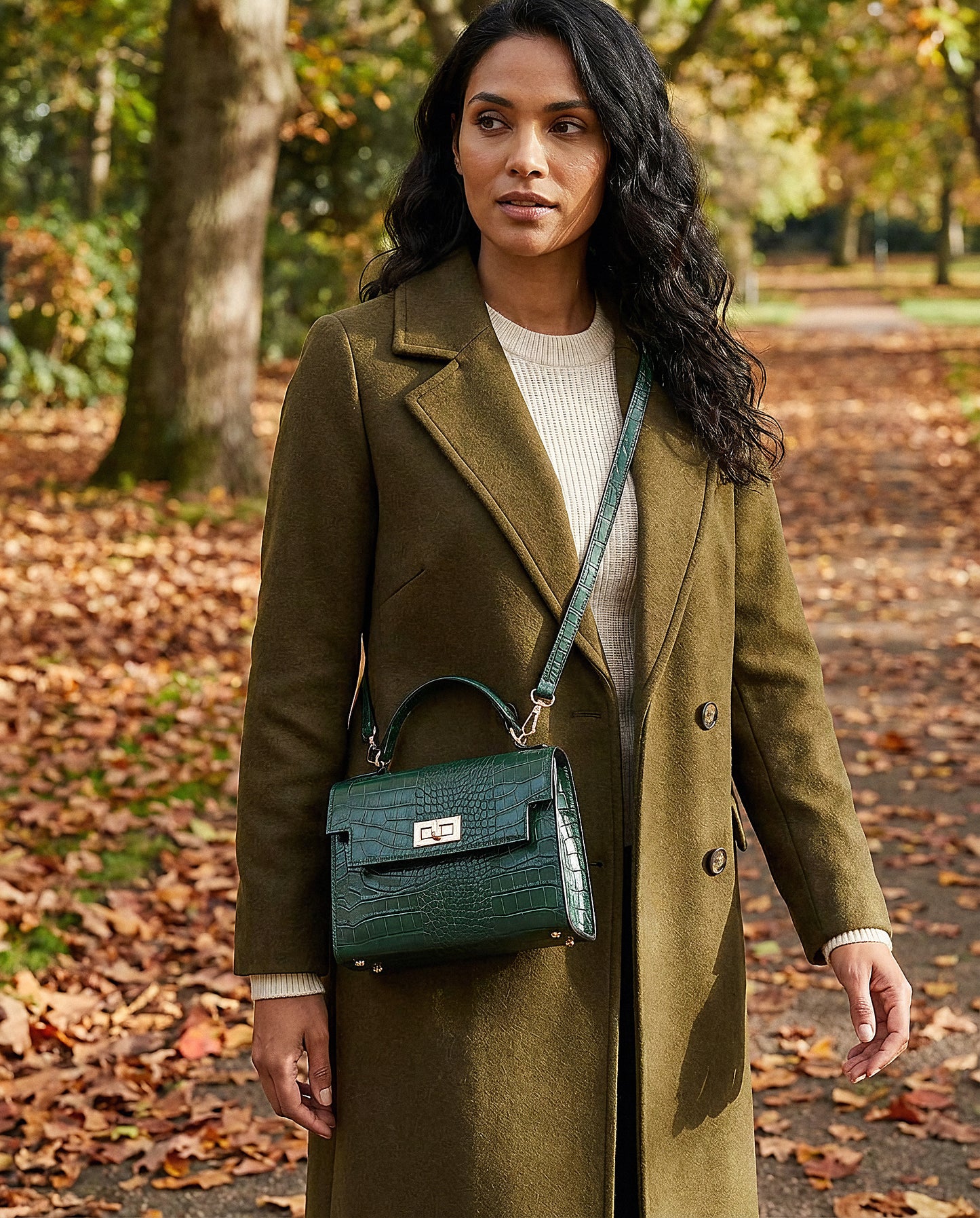 Woman with the Forest Green Margot Croc crossbody bag on an autumn park path with leaves