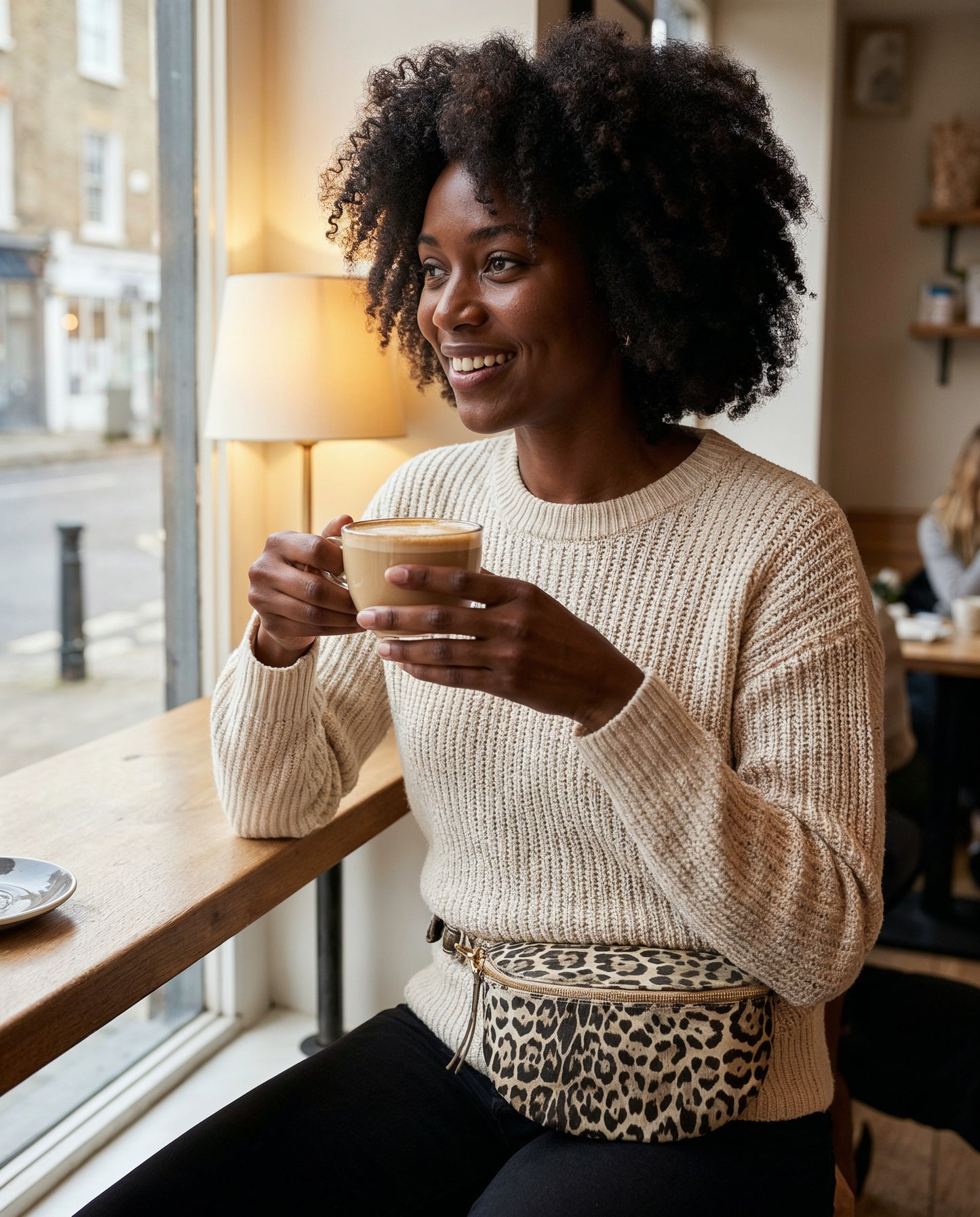 Woman with the Light Gold Leopard Romy bum bag at a cafe window seat