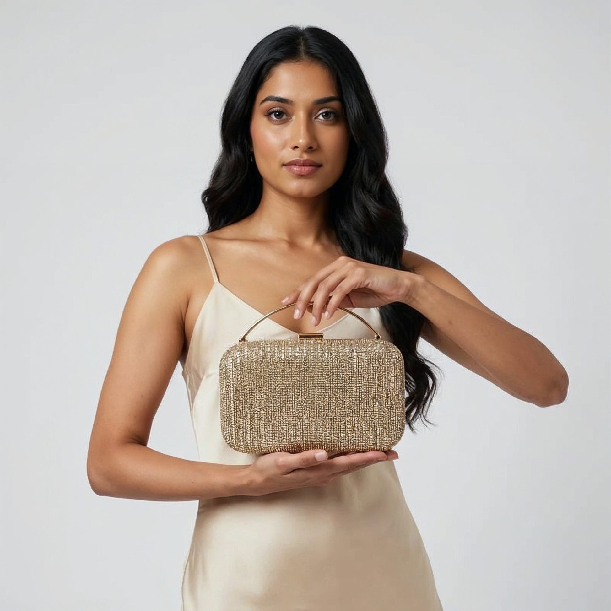 Model presenting the Gold Odette Crystal Minaudière Clutch on her open palm, studio shot