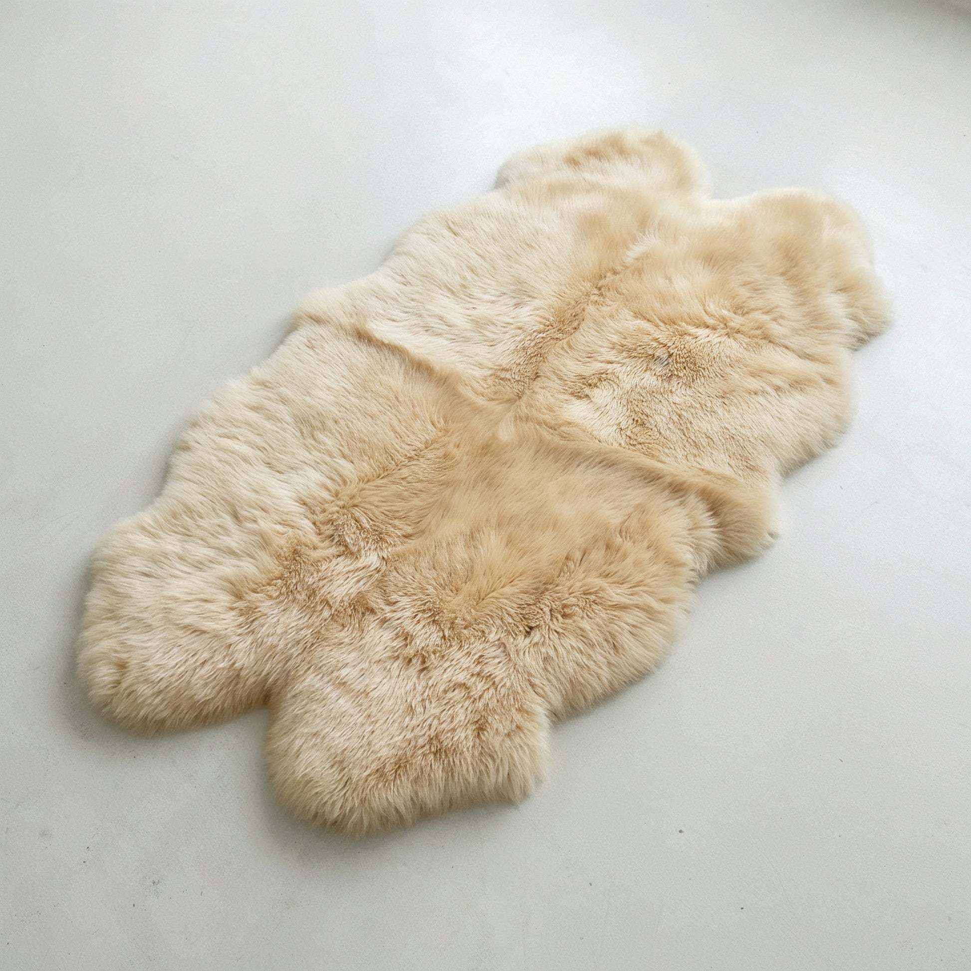Champagne quad New Zealand sheepskin rug laid flat, four-pelt silhouette