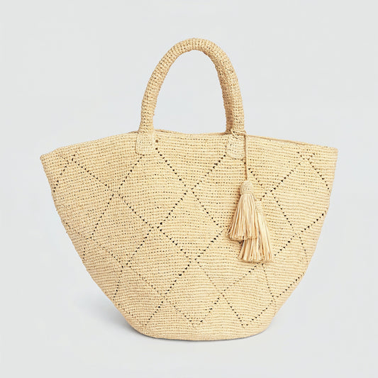 Amandine natural raffia basket tote with leather tassel on a light grey studio background