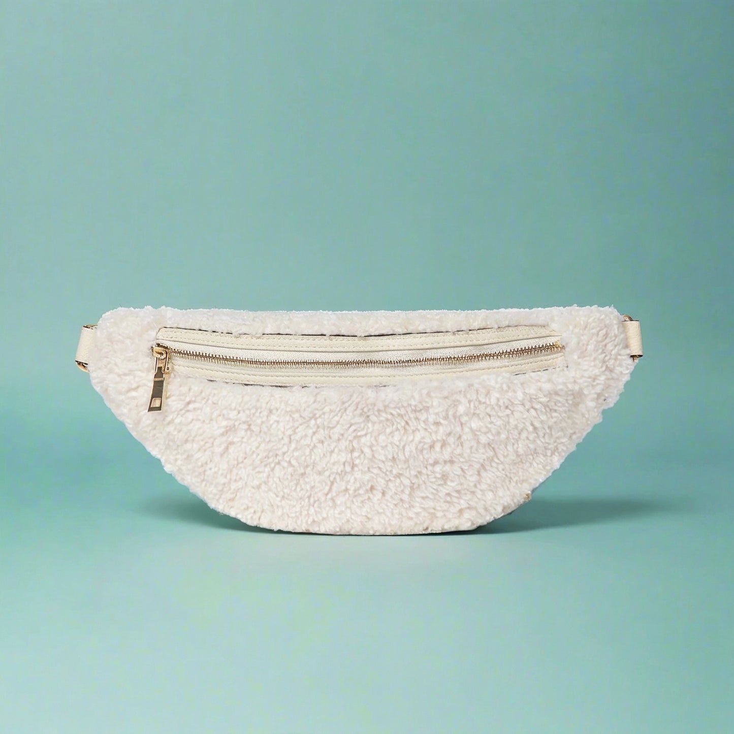 Nevina shearling and leather bum bag in white on a teal studio background