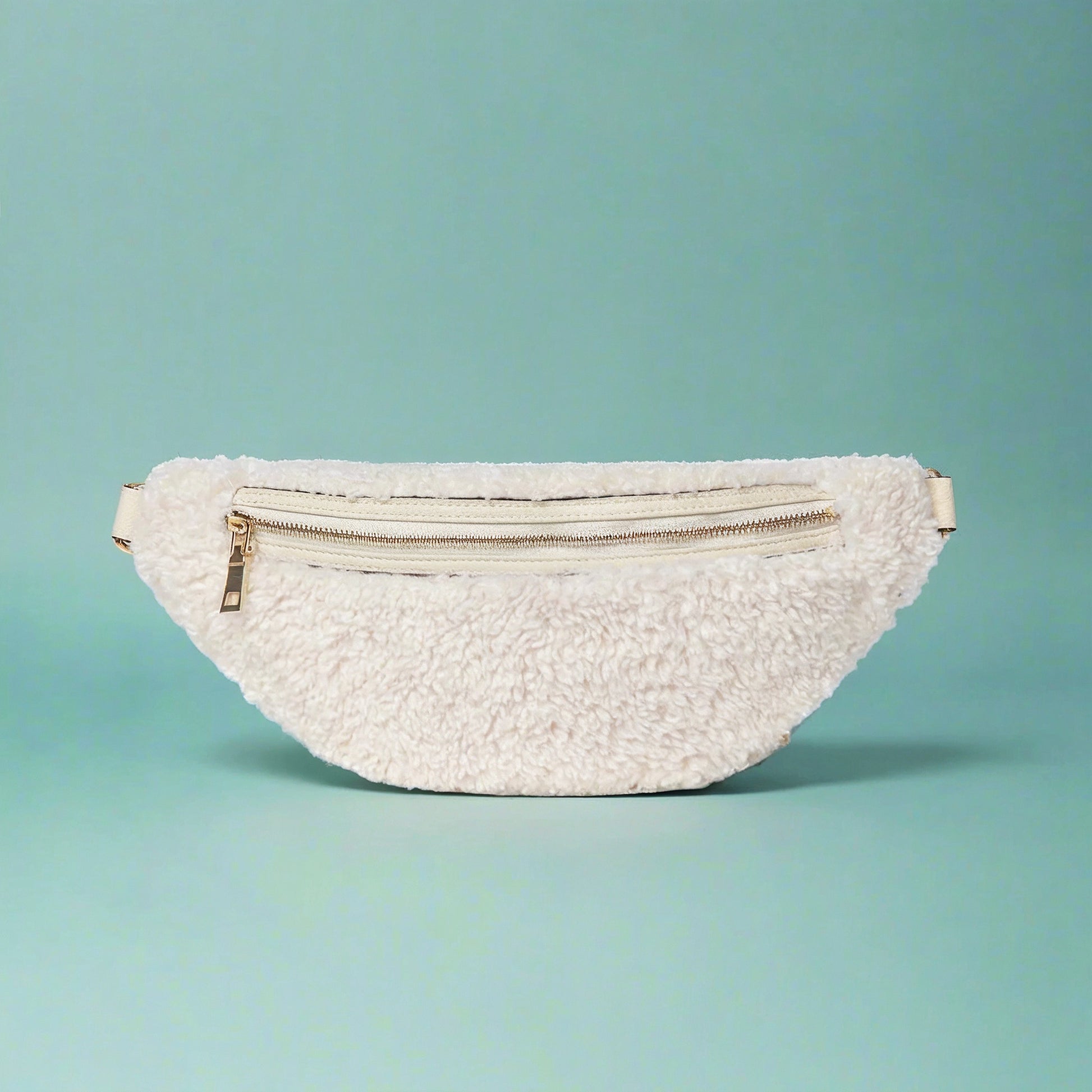 Nevina shearling and leather bum bag in white on a teal studio background