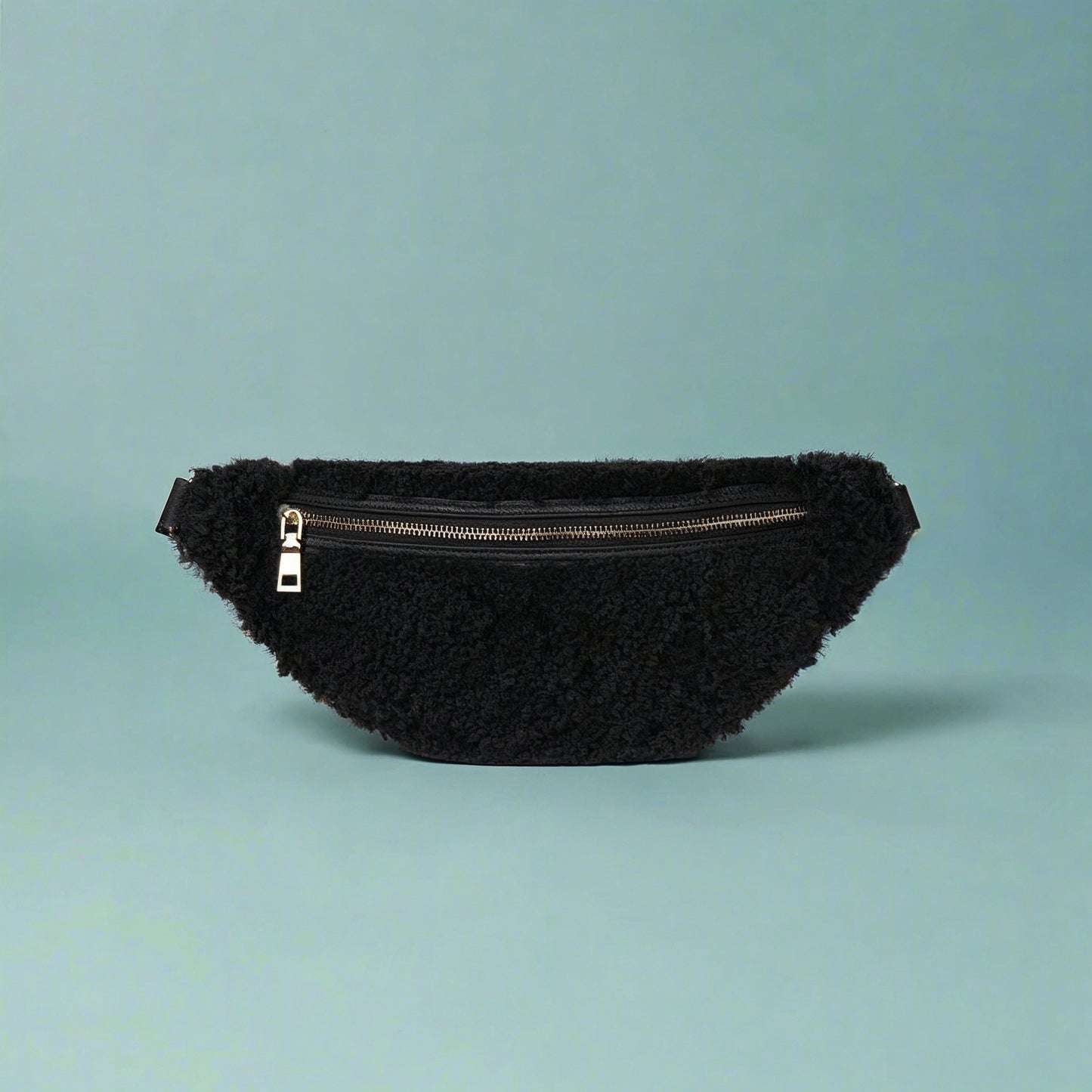Nevina shearling and leather bum bag in black on a teal studio background