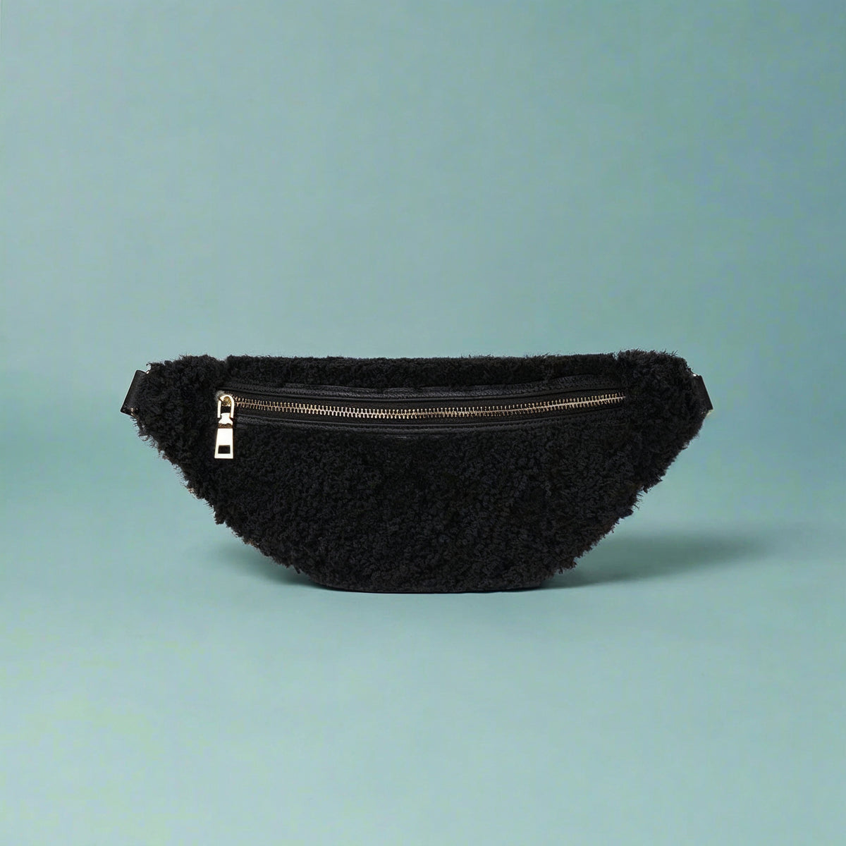 Nevina shearling and leather bum bag in black on a teal studio background