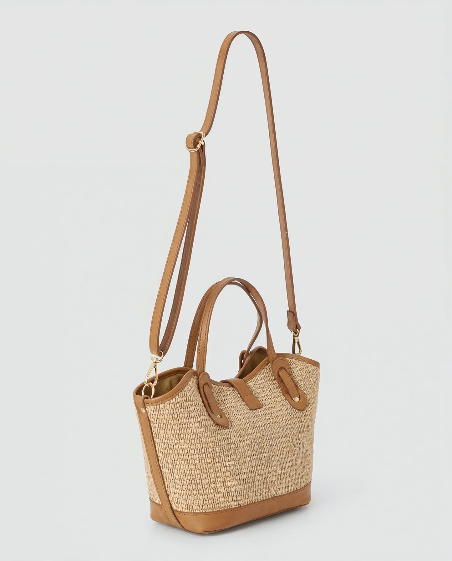 Sorrento raffia tote at three-quarter angle with detachable crossbody strap, light grey studio background