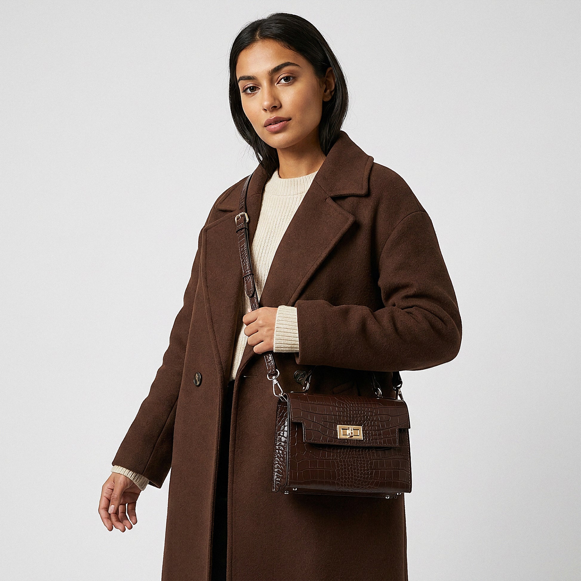 Model carrying the Chocolate Margot Croc crossbody bag on her shoulder, studio shot