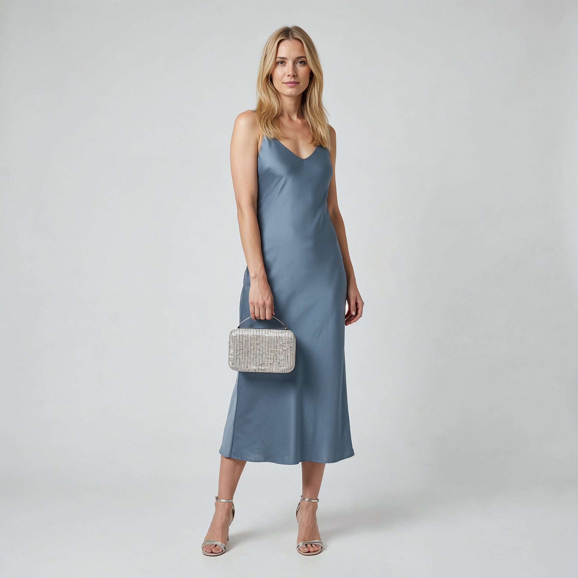 Model holding the Silver Odette Crystal Minaudière Clutch by its top handle, studio shot