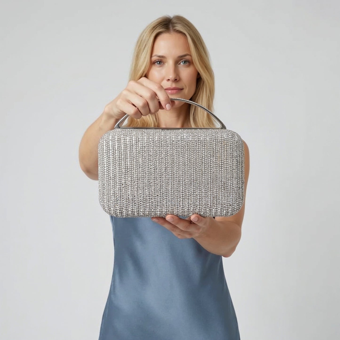 Model presenting the Silver Odette Crystal Minaudière Clutch to the camera, studio hero shot
