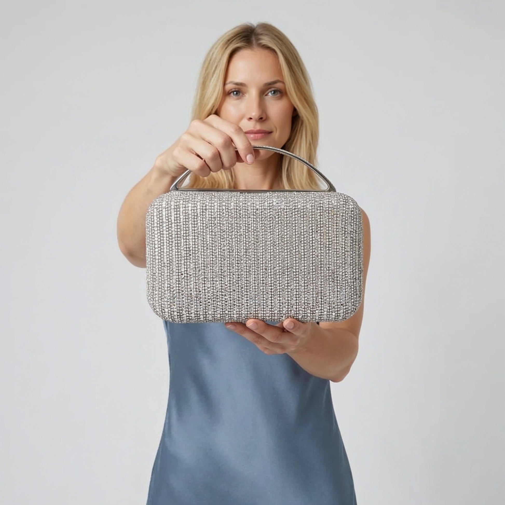 Model presenting the Silver Odette Crystal Minaudière Clutch to the camera, studio hero shot