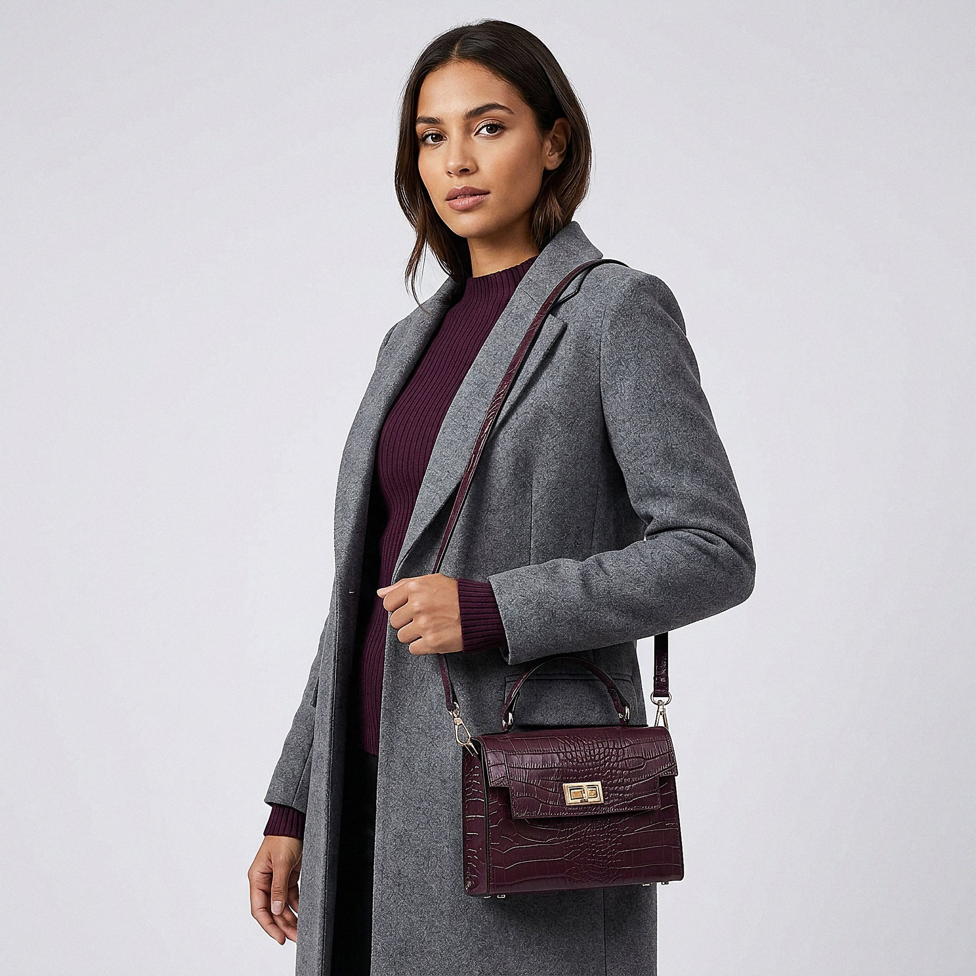 Model carrying the Aubergine Margot Croc crossbody bag on her shoulder, studio shot