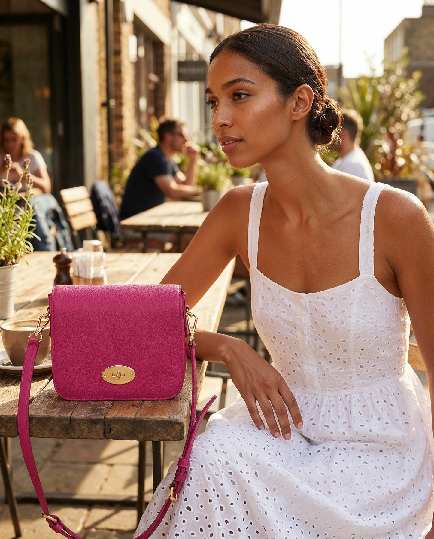 Woman with the Fuchsia Chiara crossbody bag at a sunny cafe terrace