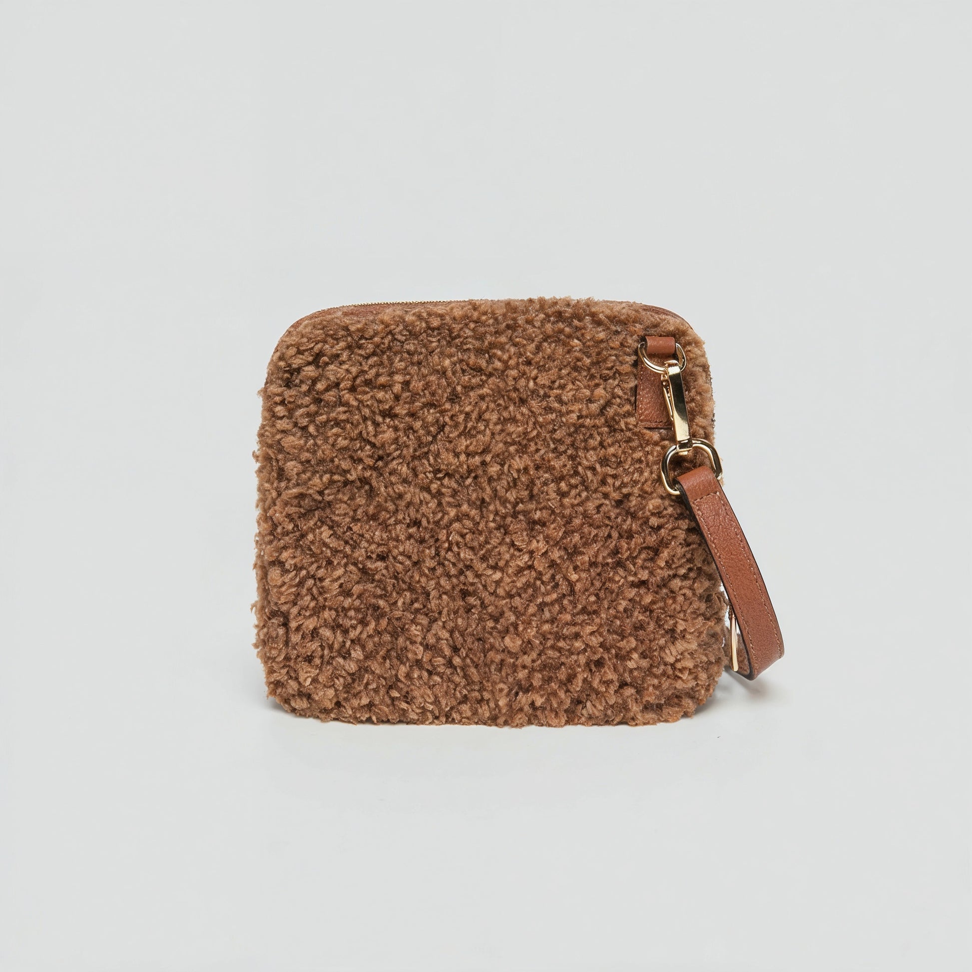 Zita faux shearling crossbody bag in chocolate brown on a light grey studio background