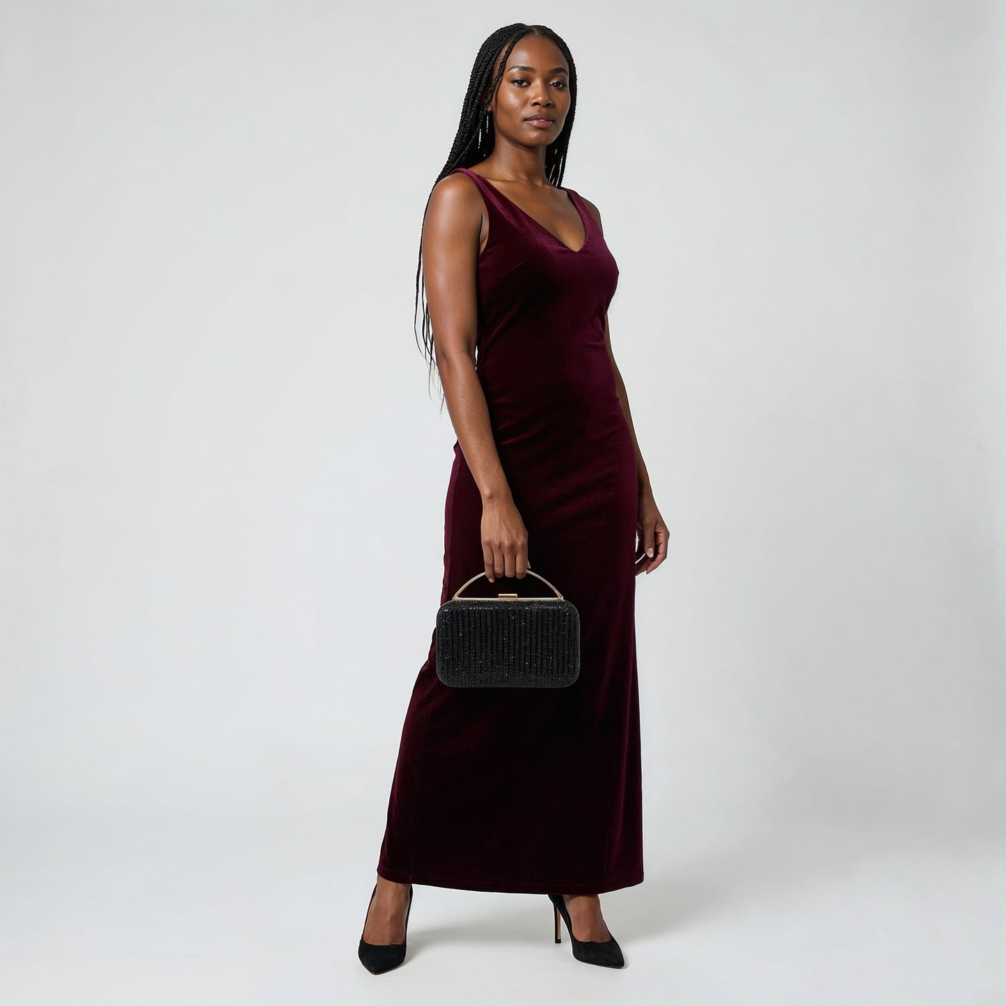 Model holding the Black Odette Crystal Minaudière Clutch by its gold top handle, studio shot