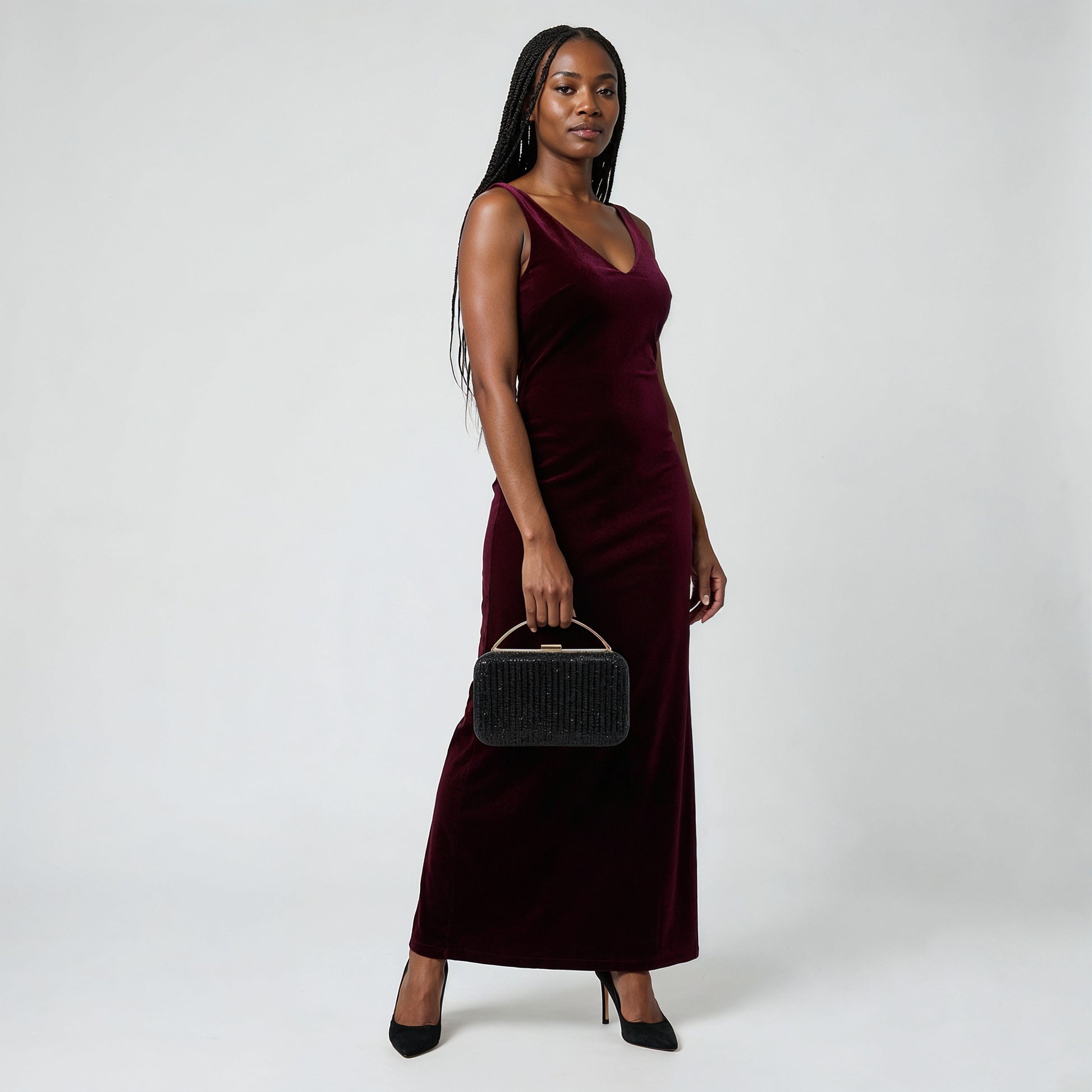 Model holding the Black Odette Crystal Minaudière Clutch by its gold top handle, studio shot