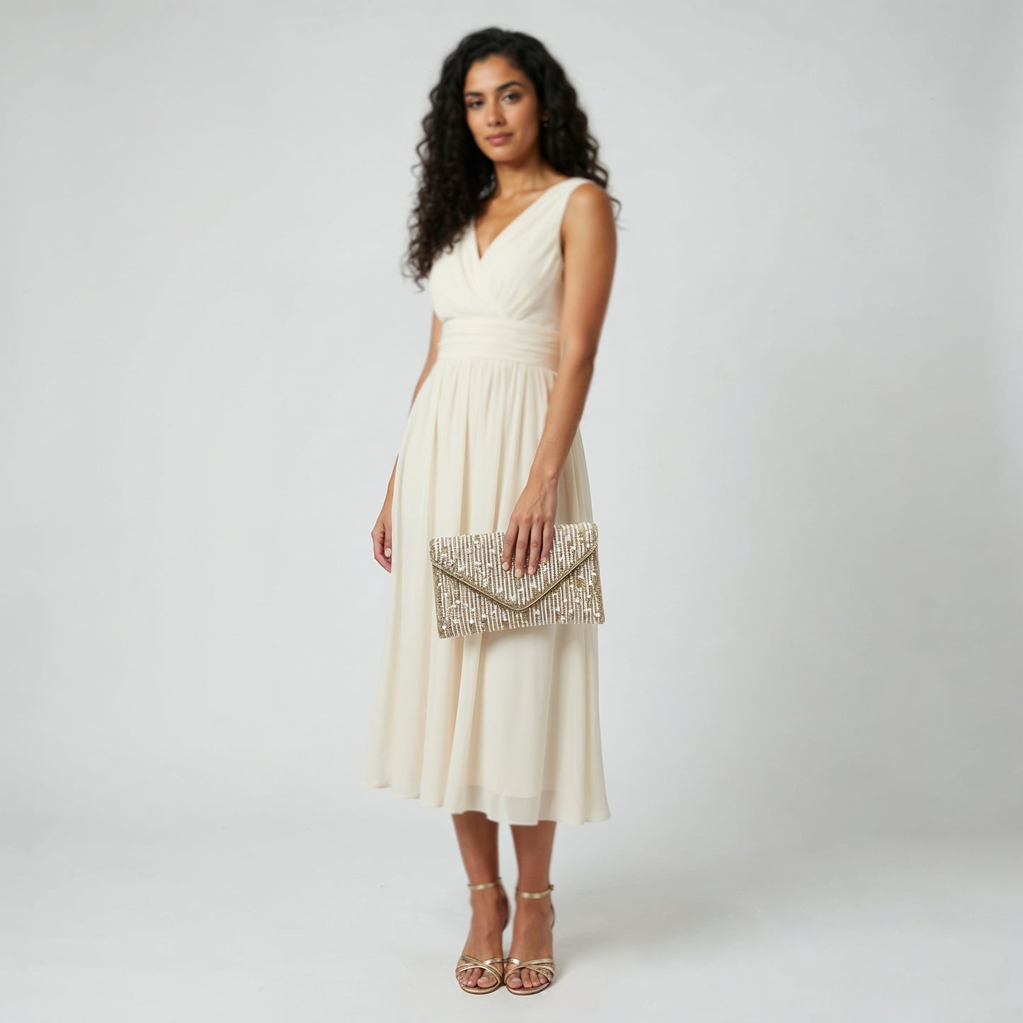 Model holding the Gold Perlette Pearl & Crystal Envelope Clutch at her side, studio shot
