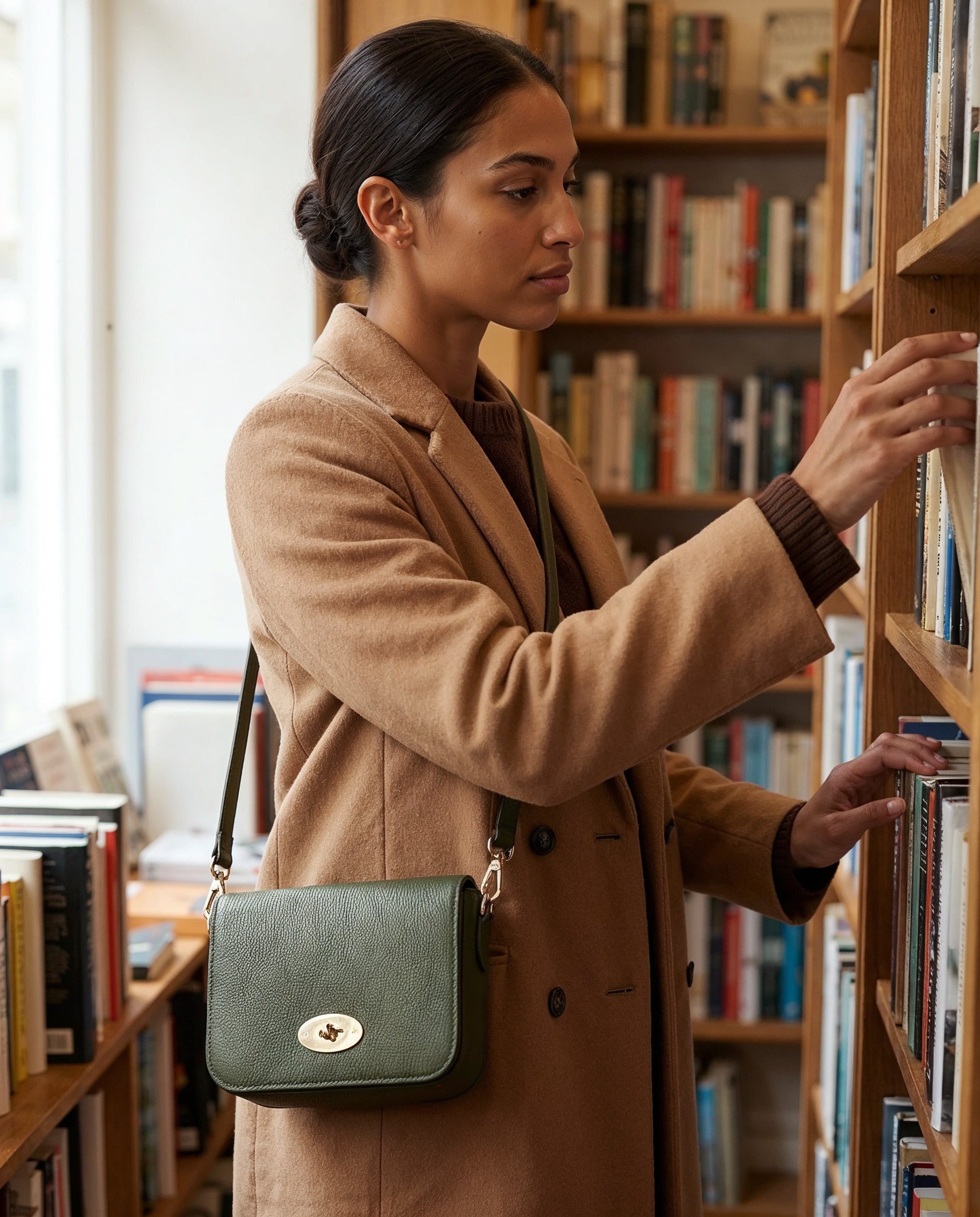 Woman with the Dark Olive Chiara crossbody bag browsing in a bookshop