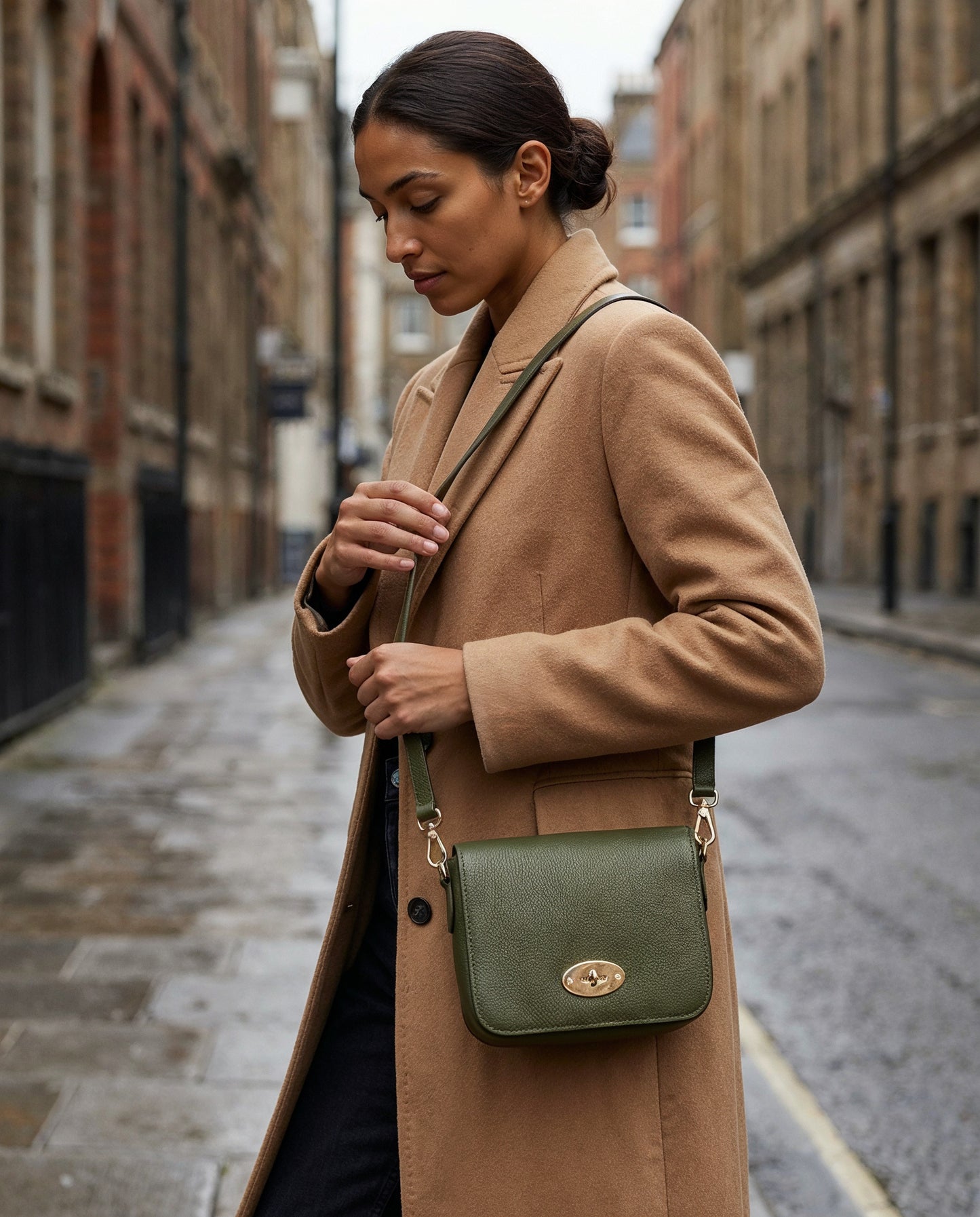 Woman with the Dark Olive Chiara crossbody bag on an overcast city street