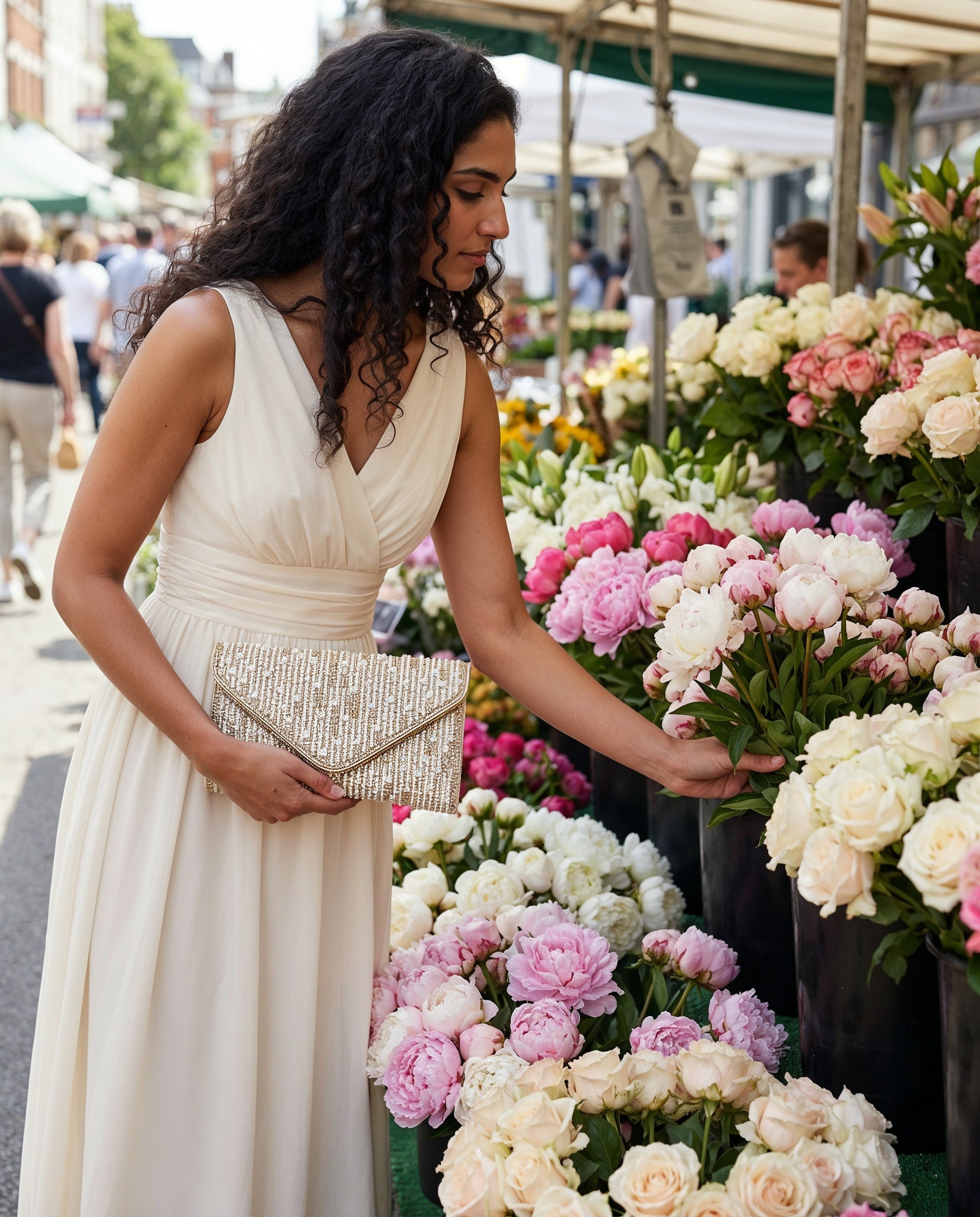 Woman holding the Gold Perlette Pearl & Crystal Envelope Clutch at a flower market stall
