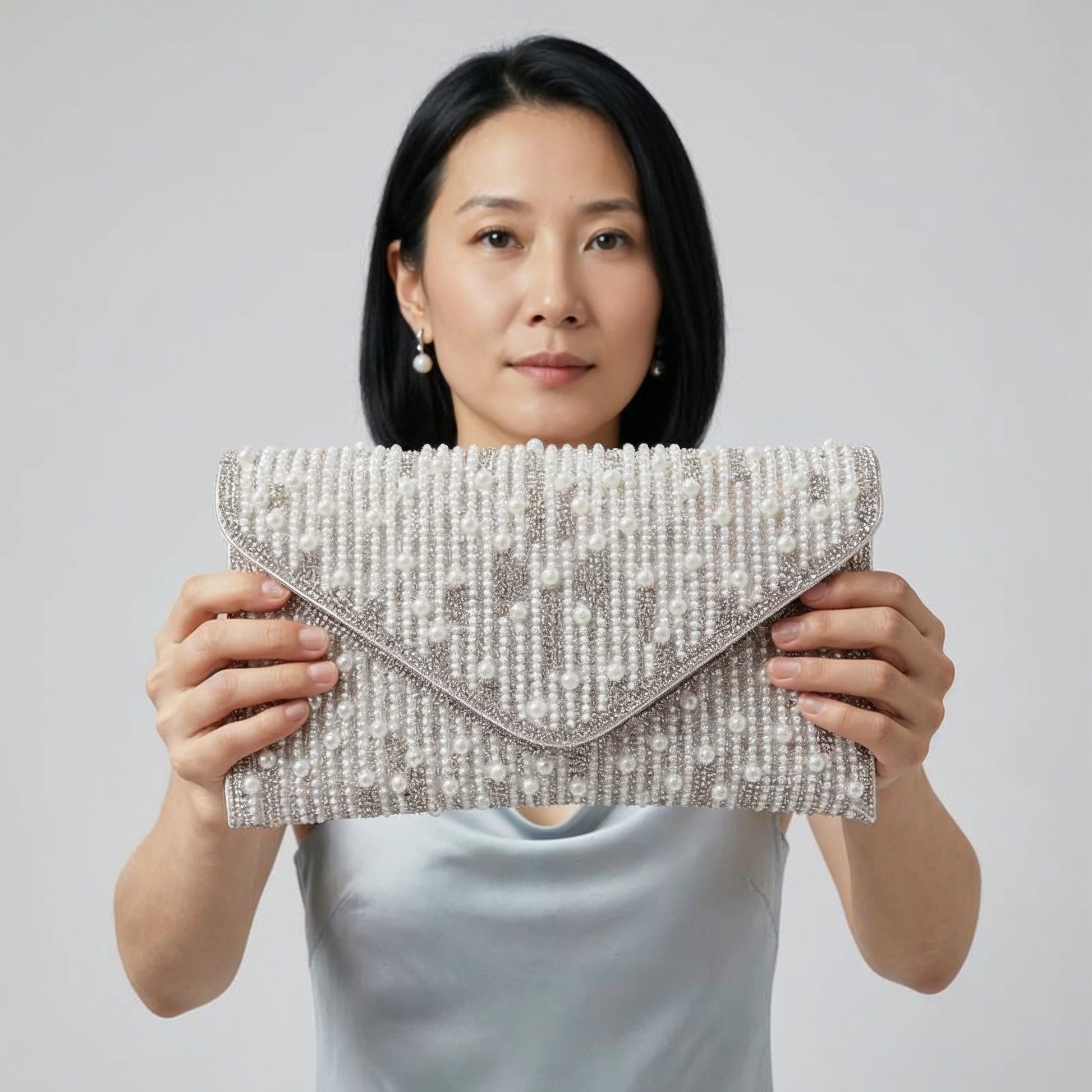 Model presenting the Silver Perlette Pearl & Crystal Envelope Clutch to the camera, studio hero shot