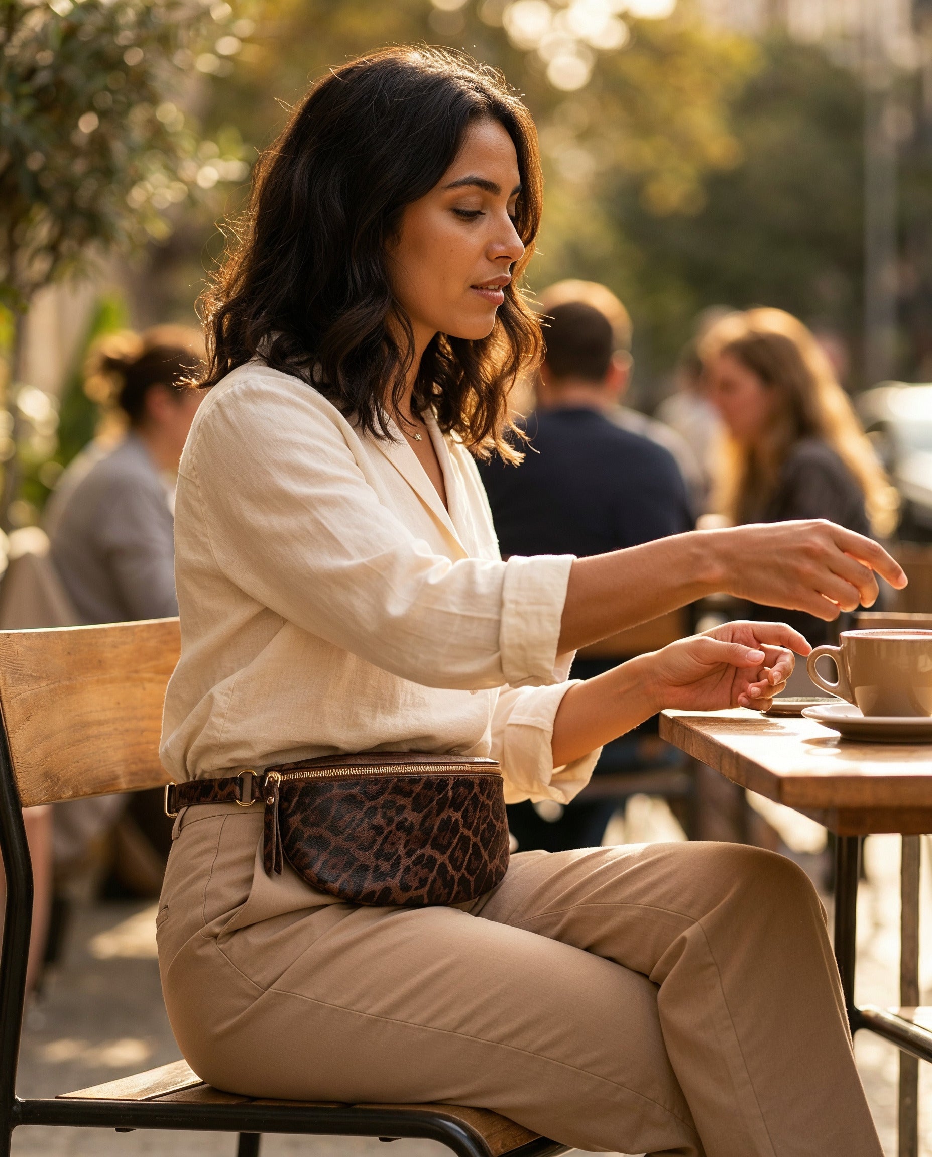 Woman wearing the Dark Tan Leopard Romy bum bag at a sunlit cafe terrace