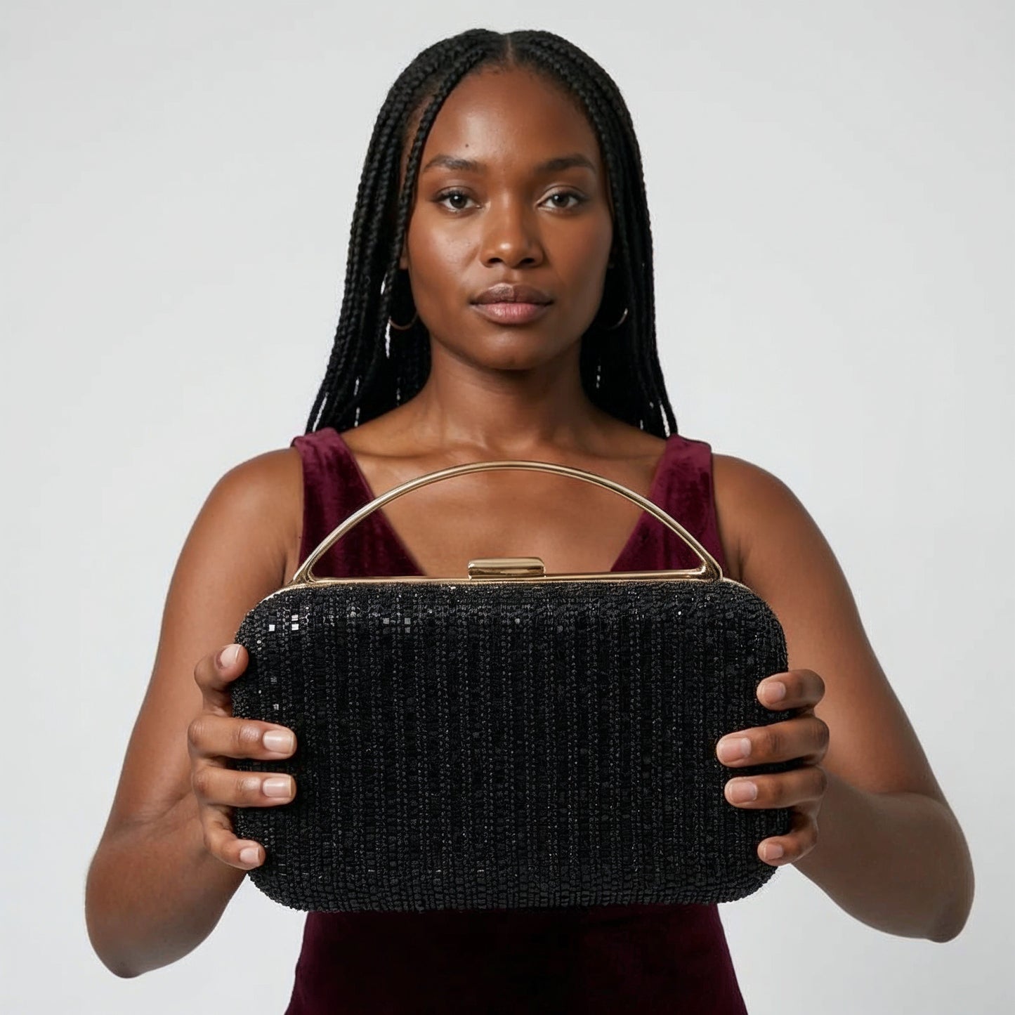 Model presenting the Black Odette Crystal Minaudière Clutch to the camera, studio hero shot