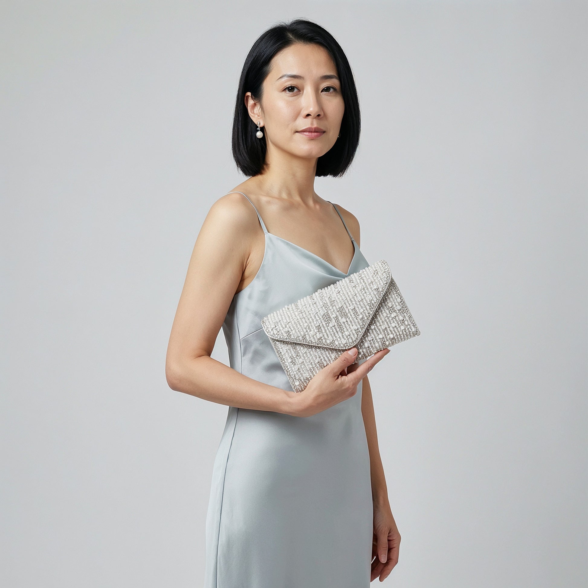 Model holding the Silver Perlette Pearl & Crystal Envelope Clutch at her side, studio shot