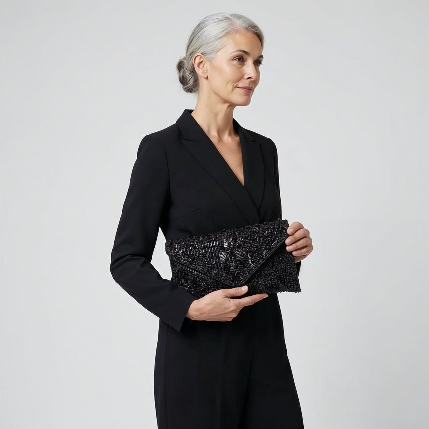 Model holding the Black Perlette Pearl & Crystal Envelope Clutch in both hands, studio shot