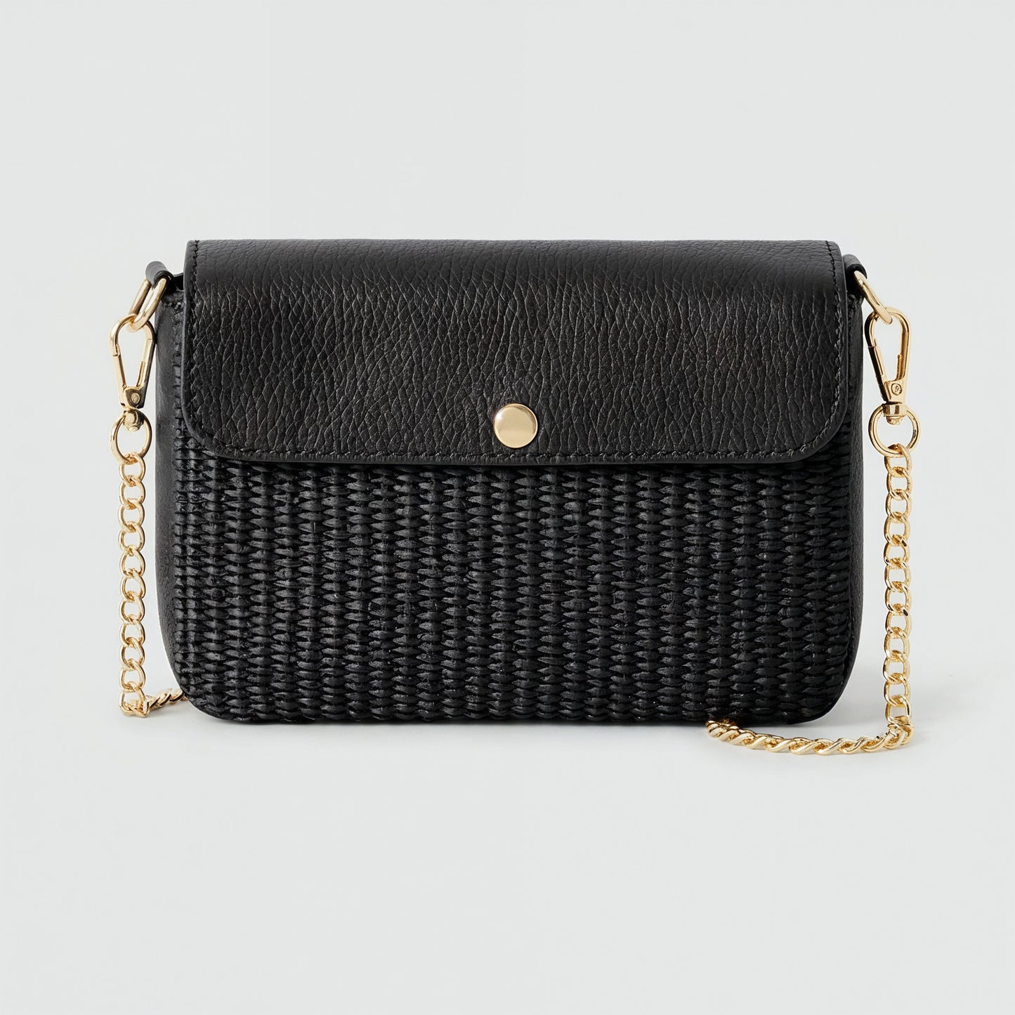 Élodie raffia and leather flap crossbody bag in black on a light grey studio background