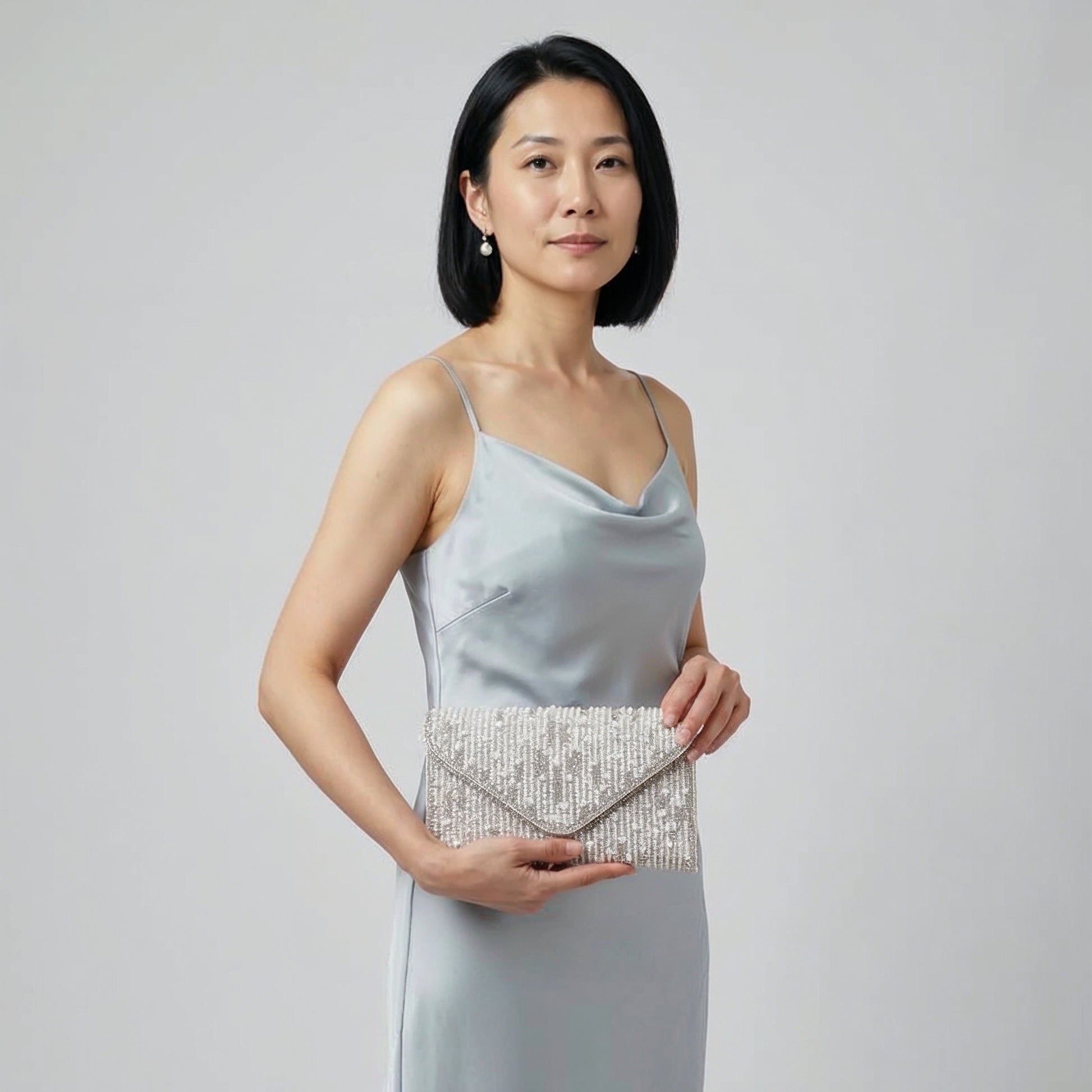Model holding the Silver Perlette Pearl & Crystal Envelope Clutch in both hands, studio shot