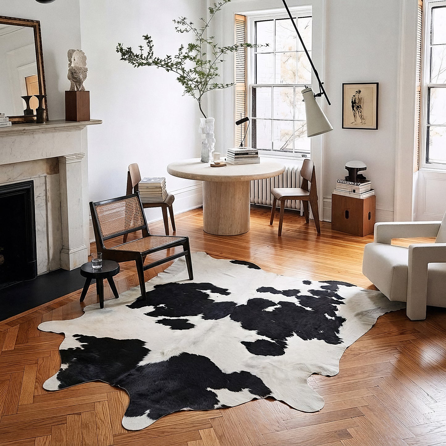 Black and white cowhide rug styled on the floor of a warm editorial dining nook