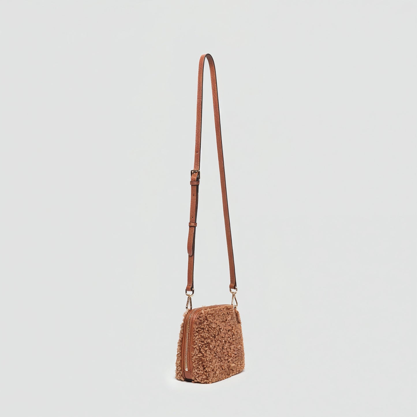 Zita faux shearling crossbody bag in tan, angled view on a light grey studio background
