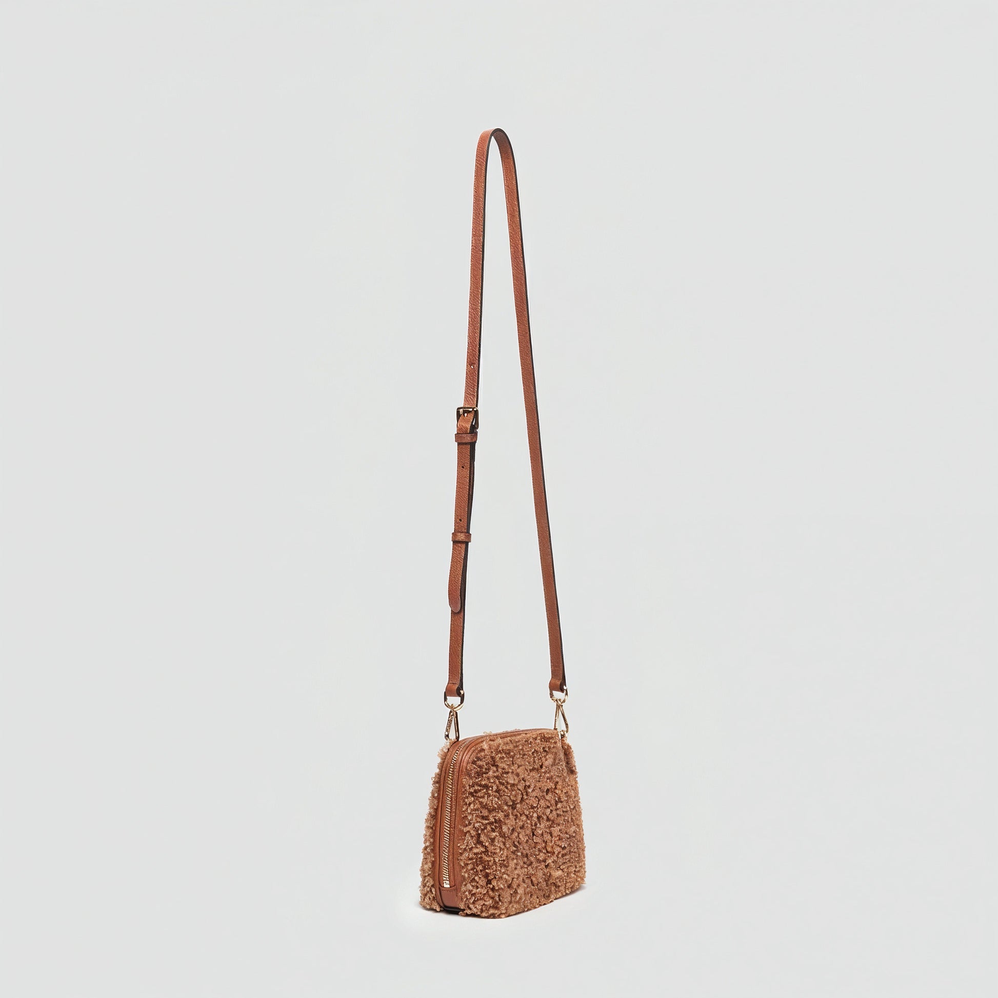 Zita faux shearling crossbody bag in tan, angled view on a light grey studio background
