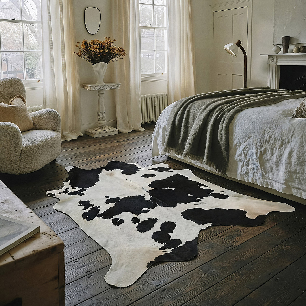 Black and white cowhide rug in a rustic wood-floor bedroom