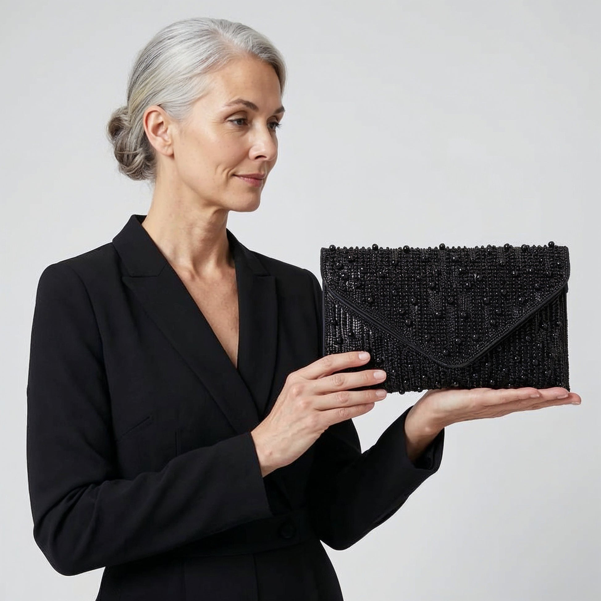 Model presenting the Black Perlette Pearl & Crystal Envelope Clutch on her open palm, studio shot