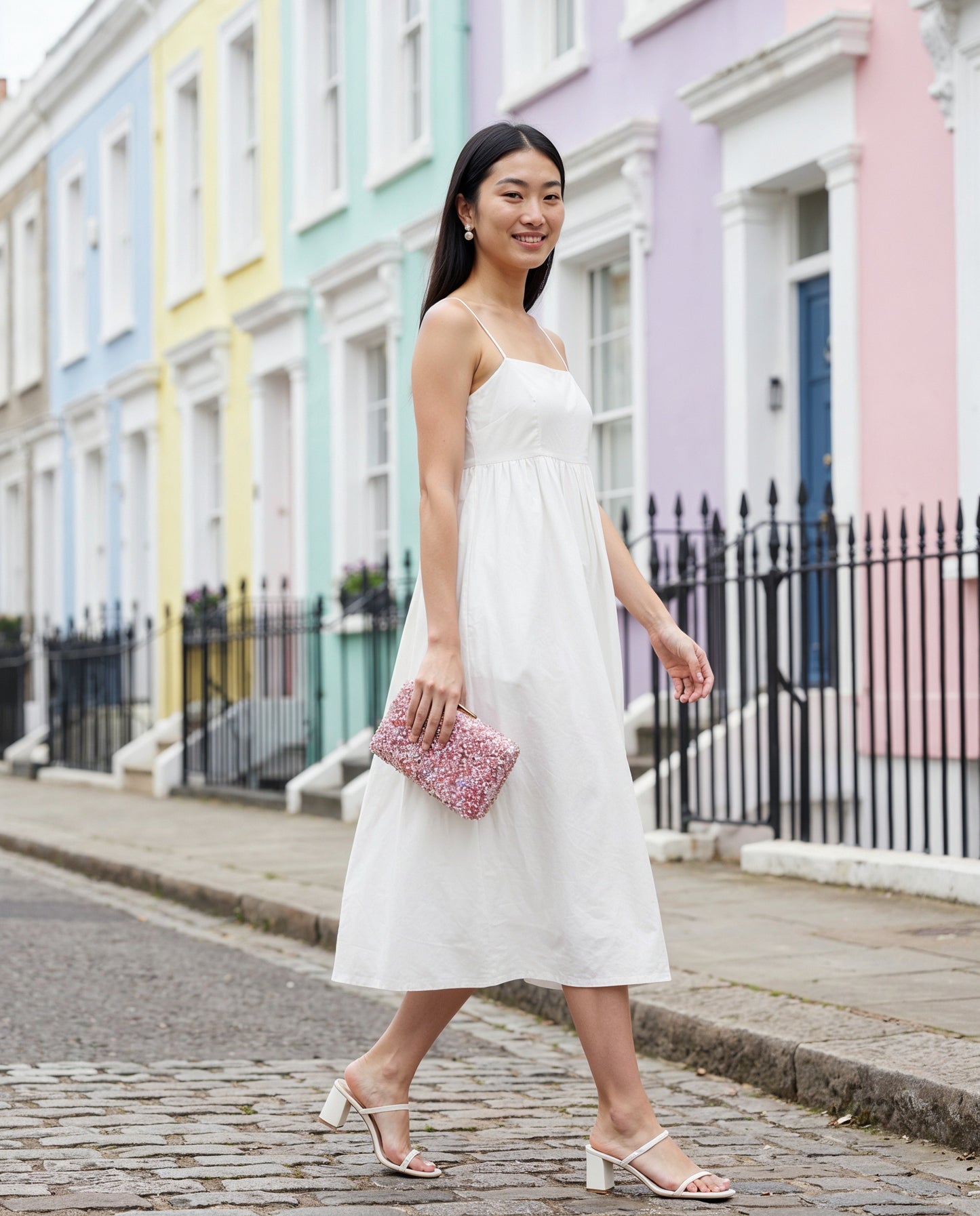 Woman carrying the Lilac Gemma Natural Stone Box Clutch past pastel houses in Notting Hill, London