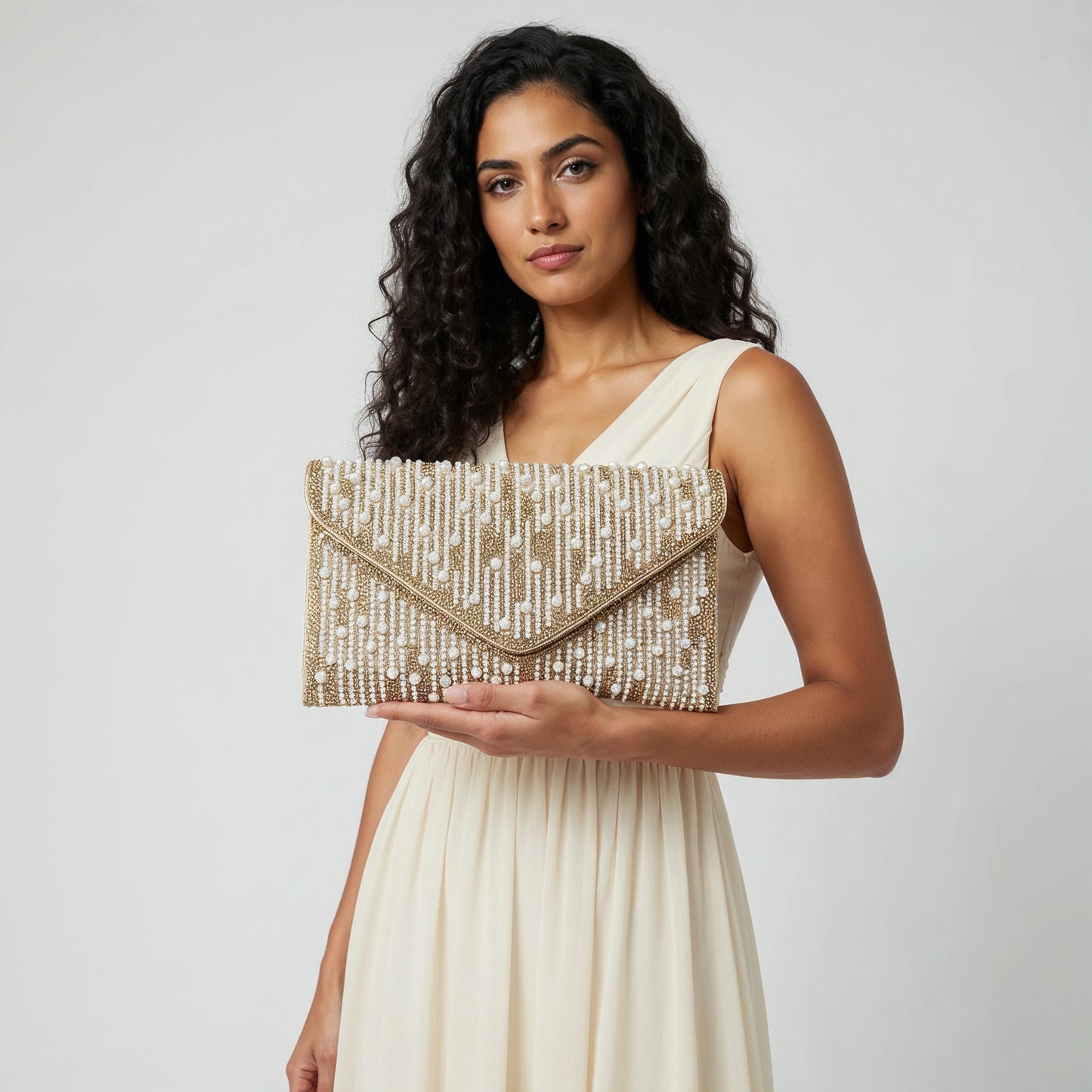 Model presenting the Gold Perlette Pearl & Crystal Envelope Clutch on her open palm, studio shot