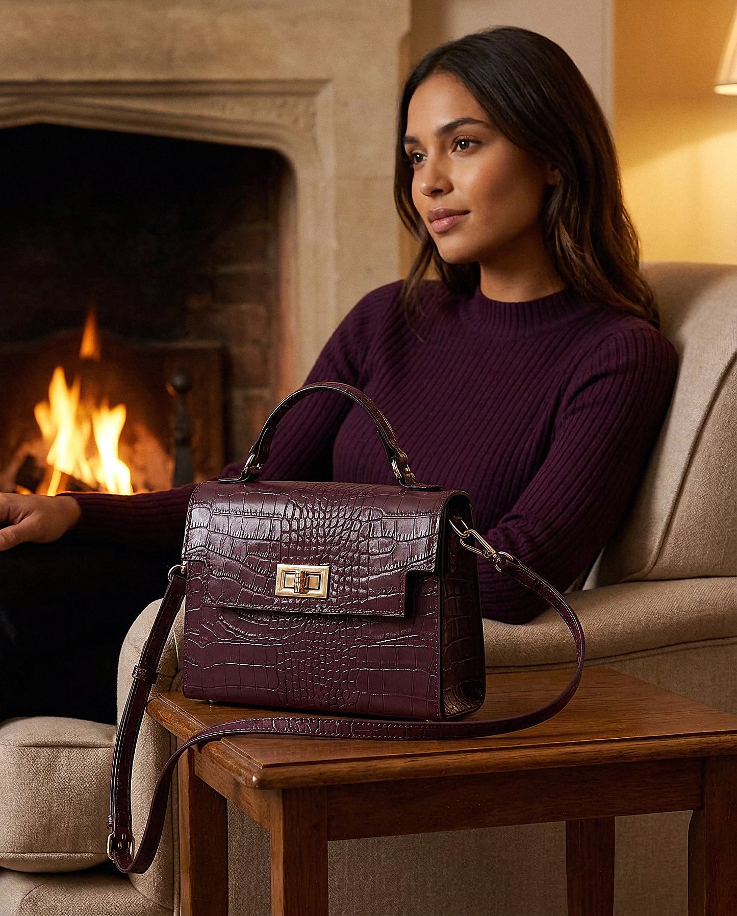 Woman with the Aubergine Margot Croc crossbody bag in a fireside living room