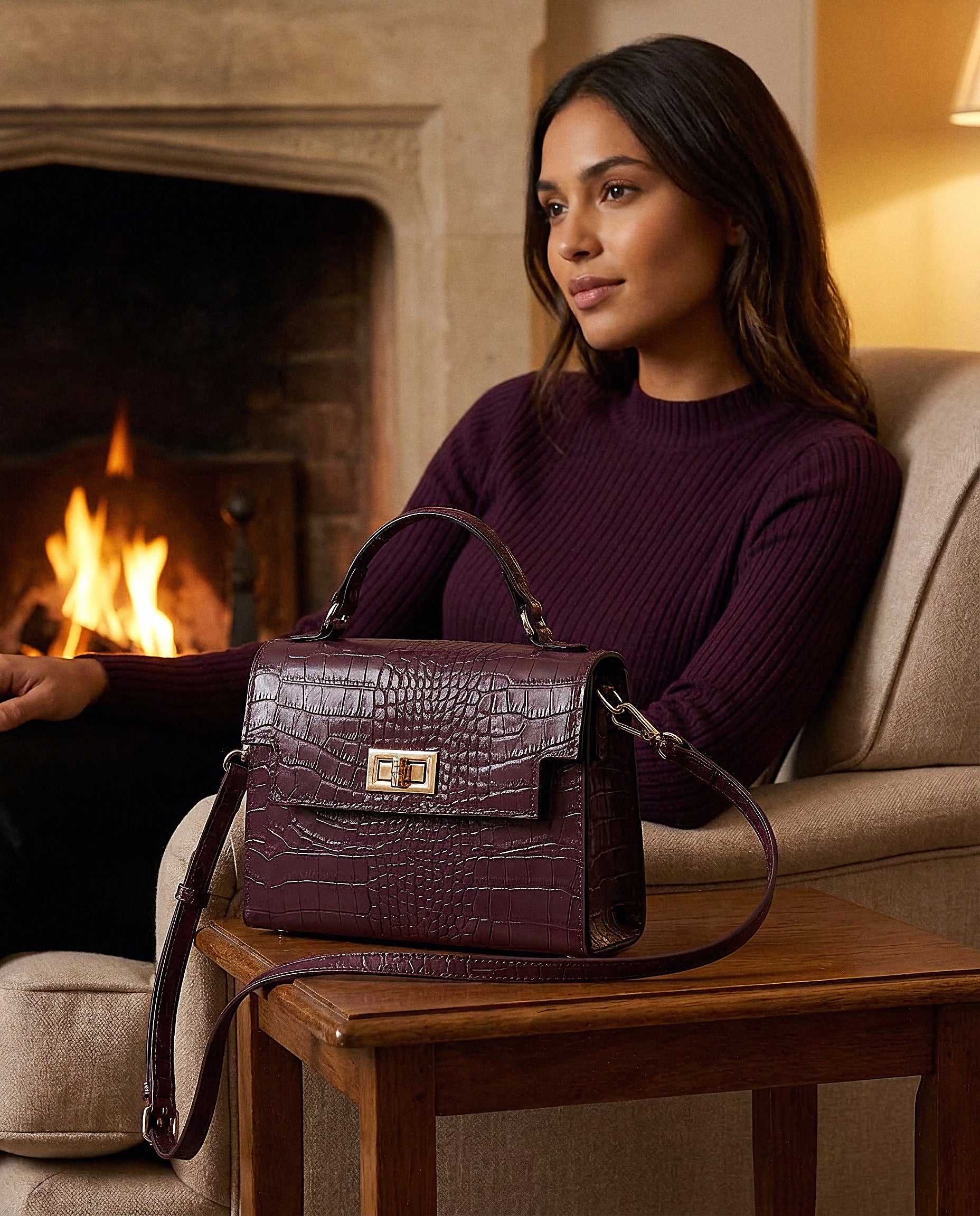 Woman with the Aubergine Margot Croc crossbody bag in a fireside living room