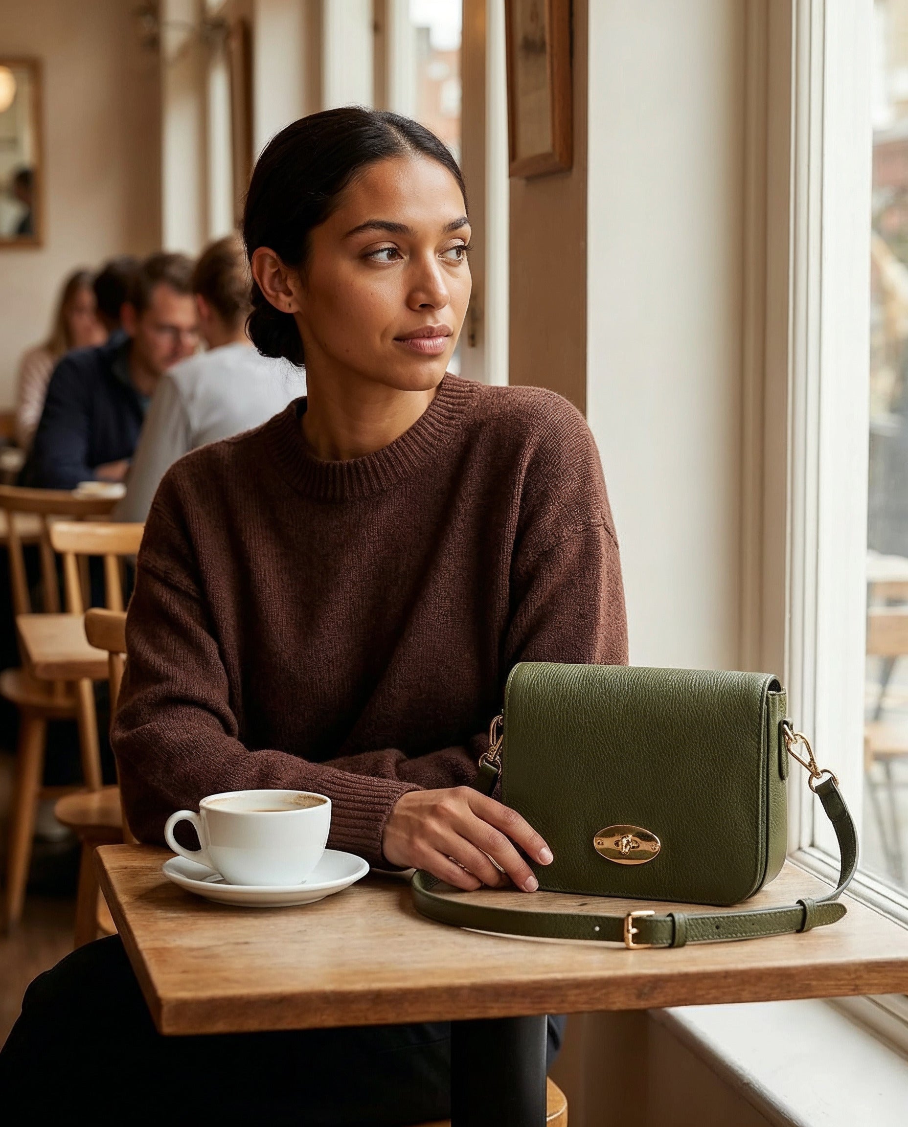 Dark Olive Chiara crossbody bag on a table at a cosy cafe