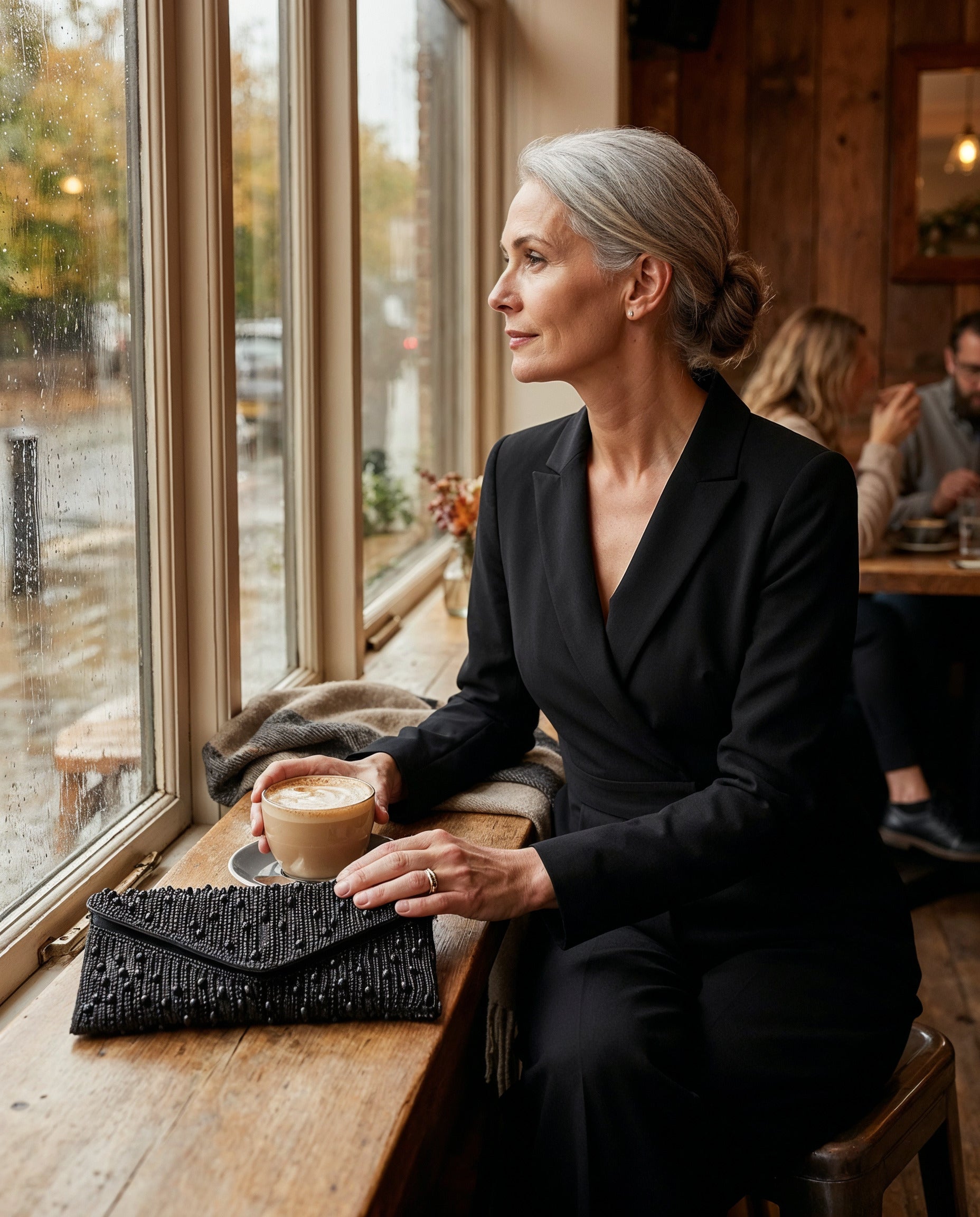 Woman with the Black Perlette Pearl & Crystal Envelope Clutch at a cosy café window seat