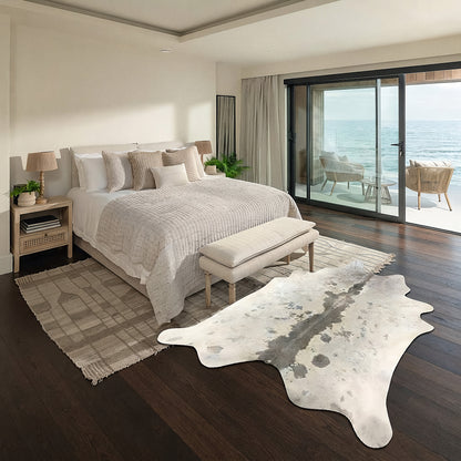 Ivory cowhide rug with grey dorsal stripe styled on the floor of a coastal ocean-view bedroom