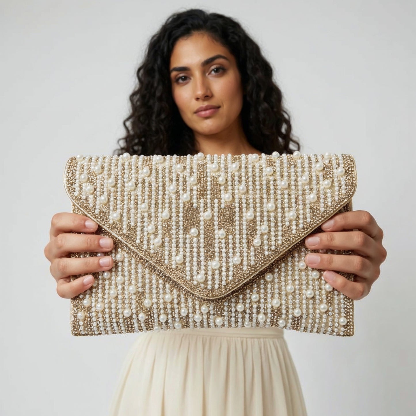 Model presenting the Gold Perlette Pearl & Crystal Envelope Clutch to the camera, studio hero shot