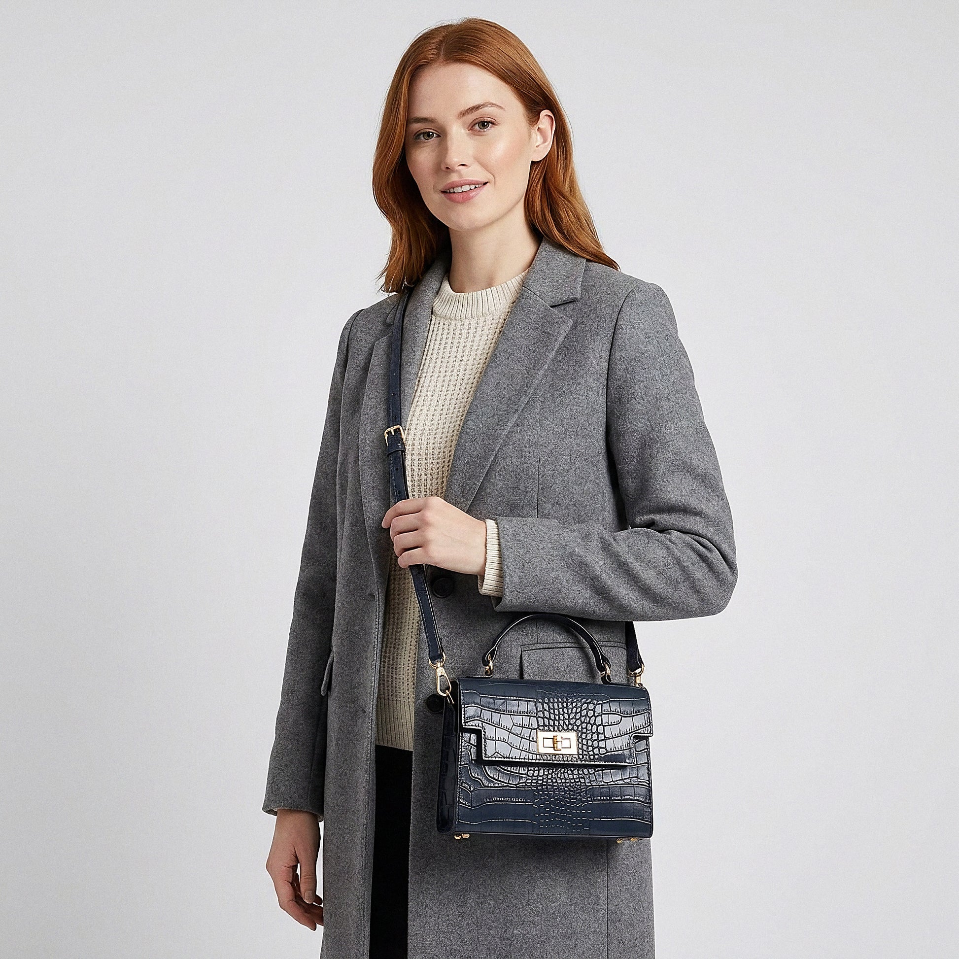 Model carrying the Navy Margot Croc crossbody bag on her shoulder, studio shot