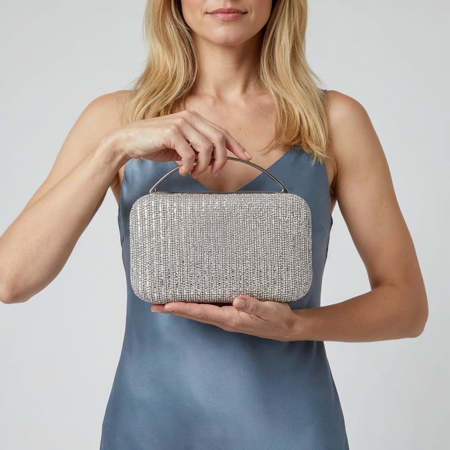 Model presenting the Silver Odette Crystal Minaudière Clutch on her open palm, studio shot