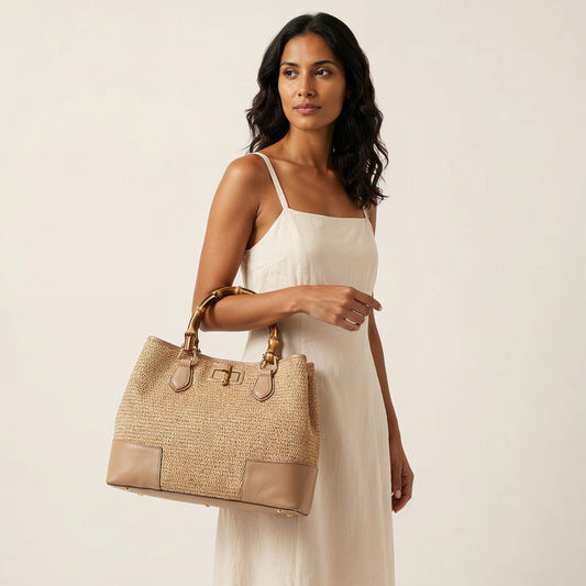 Model carrying the Light Taupe Ginevra Bamboo-Handle Raffia Bag by Clemés at the crook of her elbow, studio shot