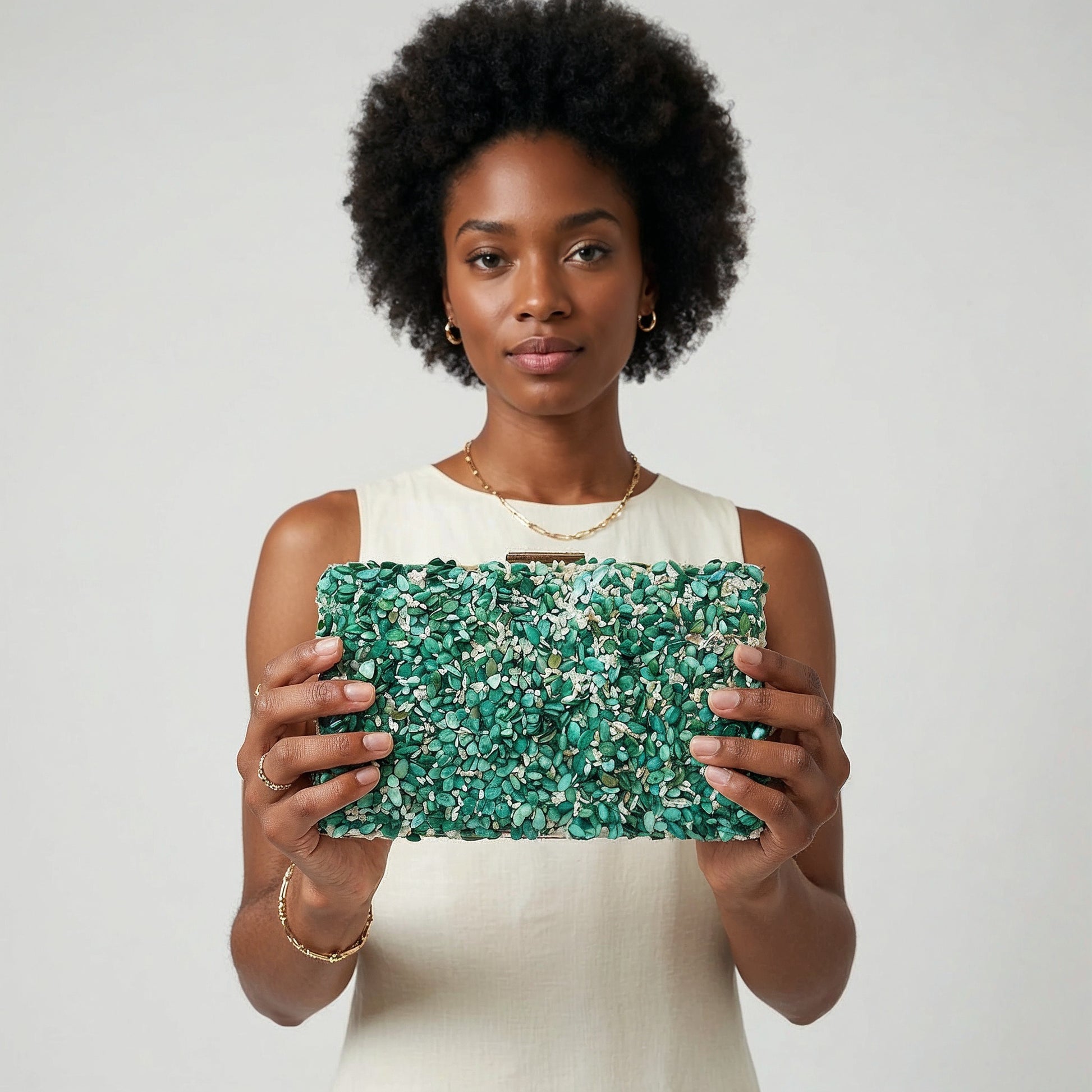 Model presenting the Turquoise Gemma Natural Stone Box Clutch to the camera, studio hero shot